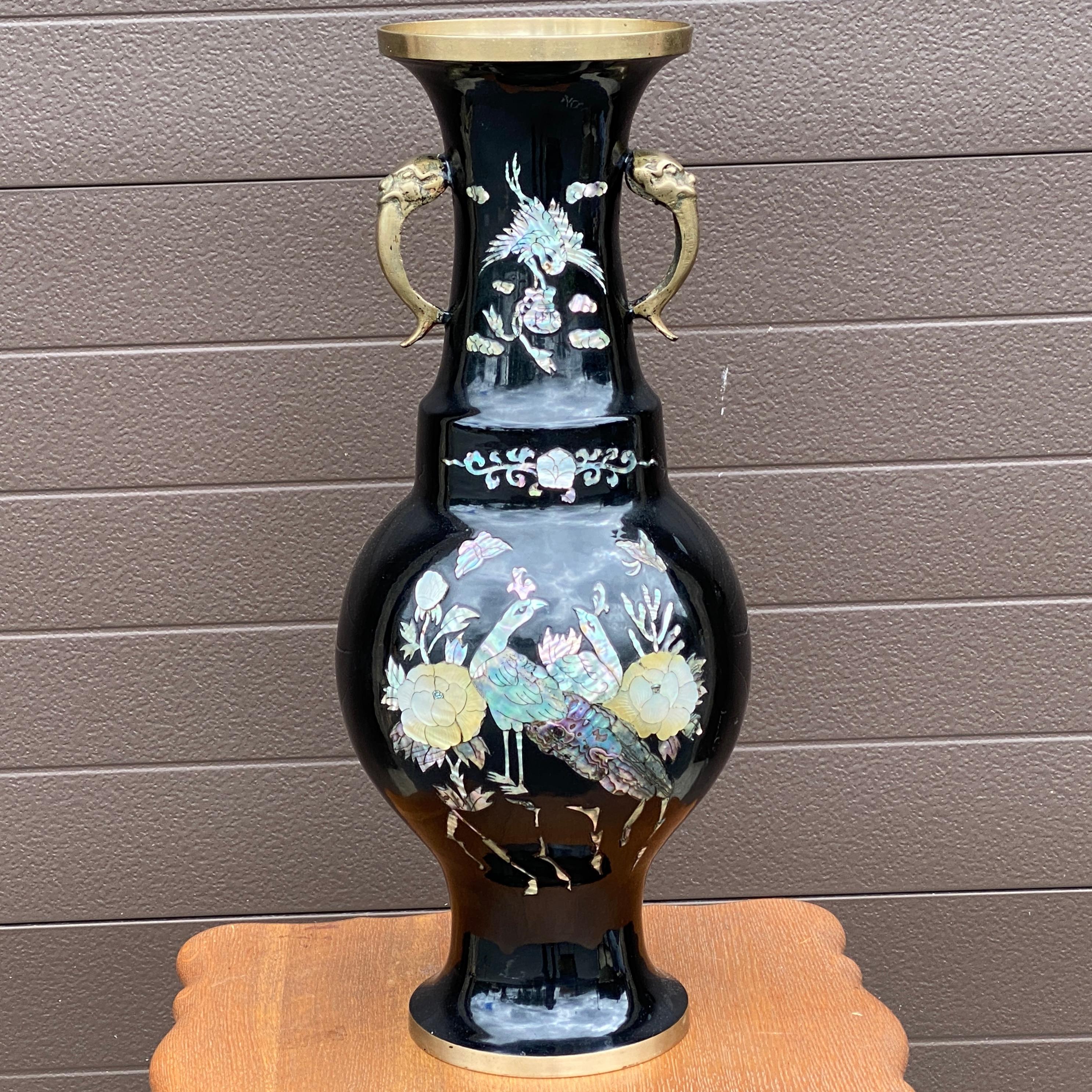 A lovely vintage Asian cloisonné vase featuring brilliant mother of pearl accents from the mid-20th century.

Large scale, having a circular top with tapered neck which leads down to a robust bulbous exterior affixed with flanking stylized figural