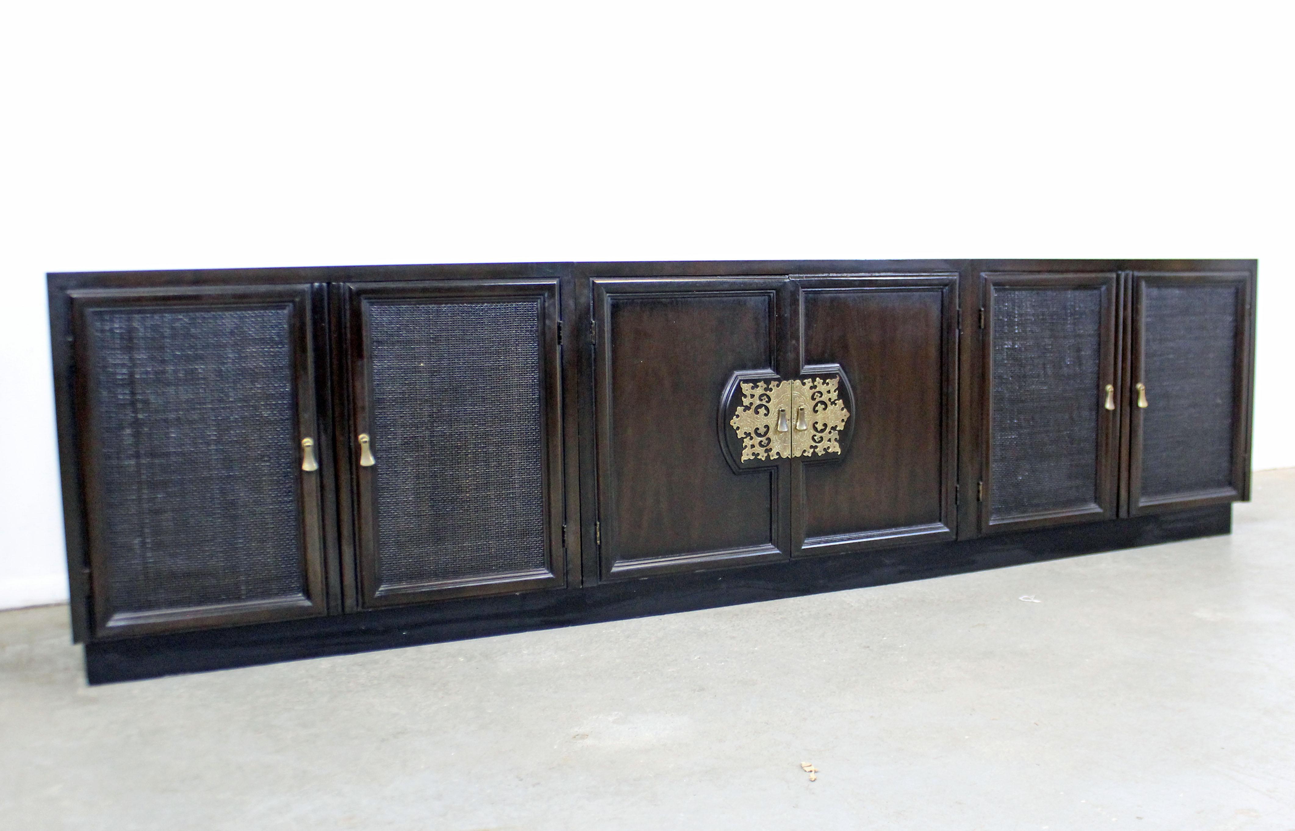 Offered is a vintage midcentury Asian-style credenza by John Stuart. This is a 4-piece credenza made of beautiful Macassar wood with brass accents. Four cabinets sit on the base. They all have adjustable inner-shelving. It is in good condition,