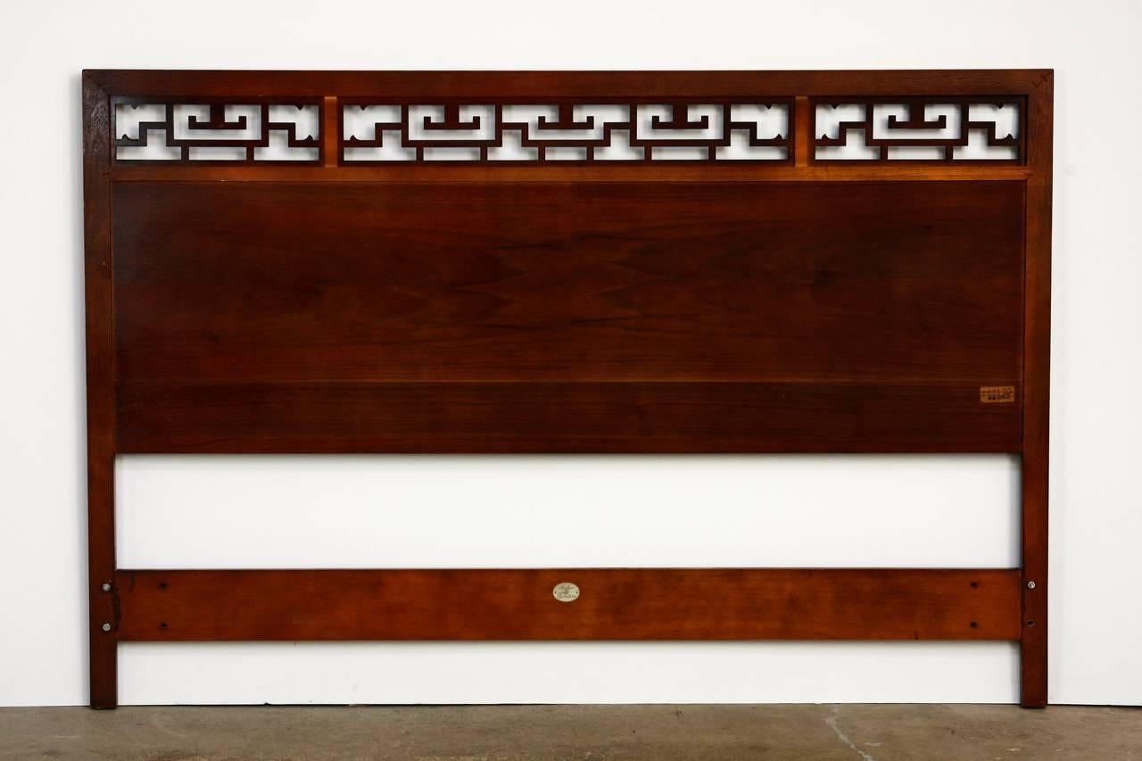 Stylish Mid-Century Modern mahogany headboard made in the Chinese Ming style taste by Baker. Features large beautifully grained match mahogany with an interesting geometric pierced open fretwork windows on top. Stamped by Baker and finished in a