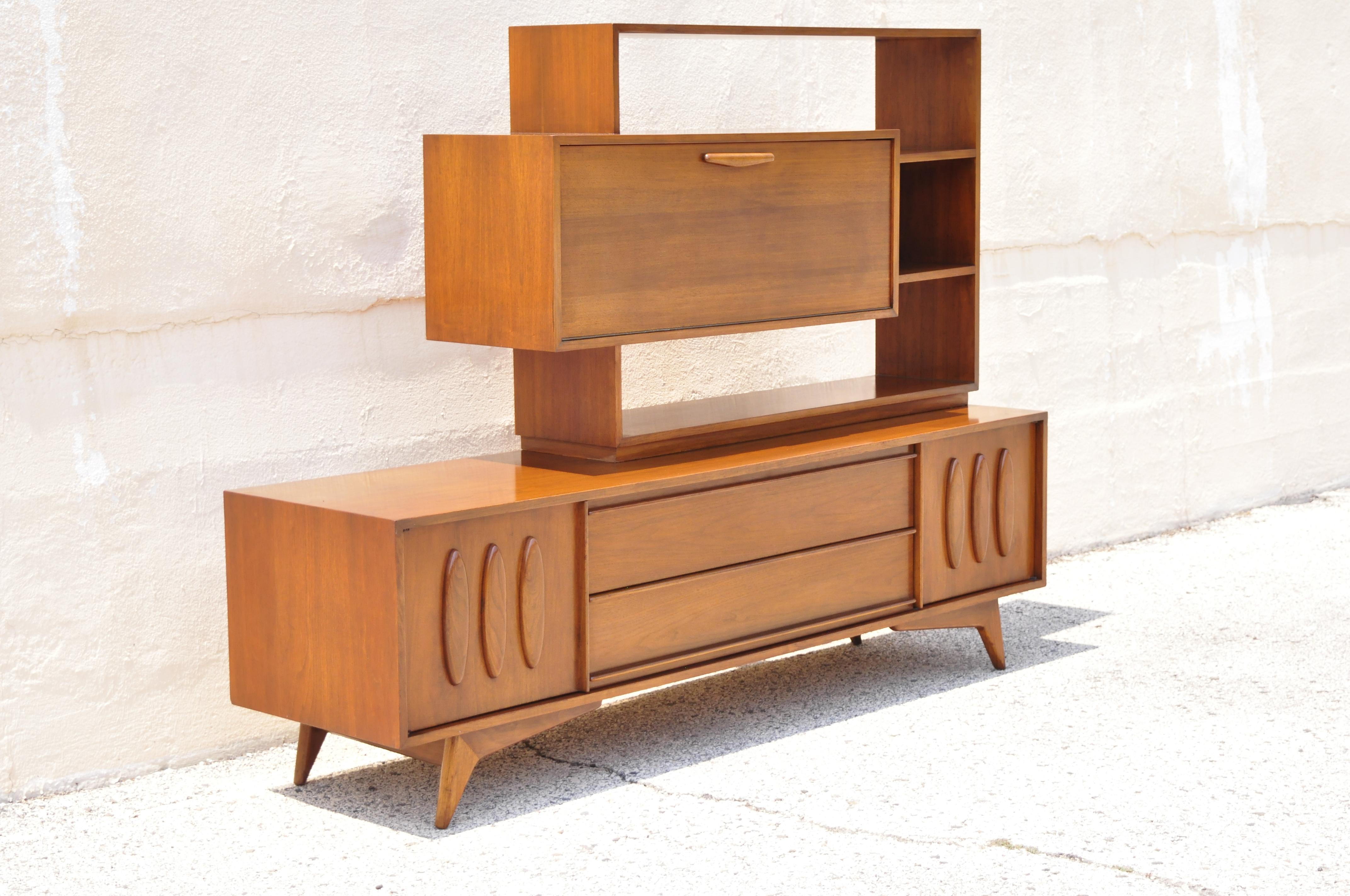 Mid-Century Modern Atomic Era walnut floating shelf bar credenza cabinet sideboard. Item features fall front mirrored bar, floating shelves, beautiful wood grain, 2 part construction, 2 swing doors, 2 dovetailed drawers, tapered legs, clean