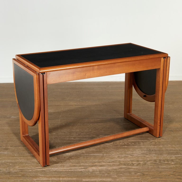 Mid-century Augusto Savini for Pozzi drop-leaf desk. Introduced 1965, dark stained oak, inset leather top, with three frieze drawers and open cubby, drop-leaf side extenders, unmarked.

Dimensions:
32