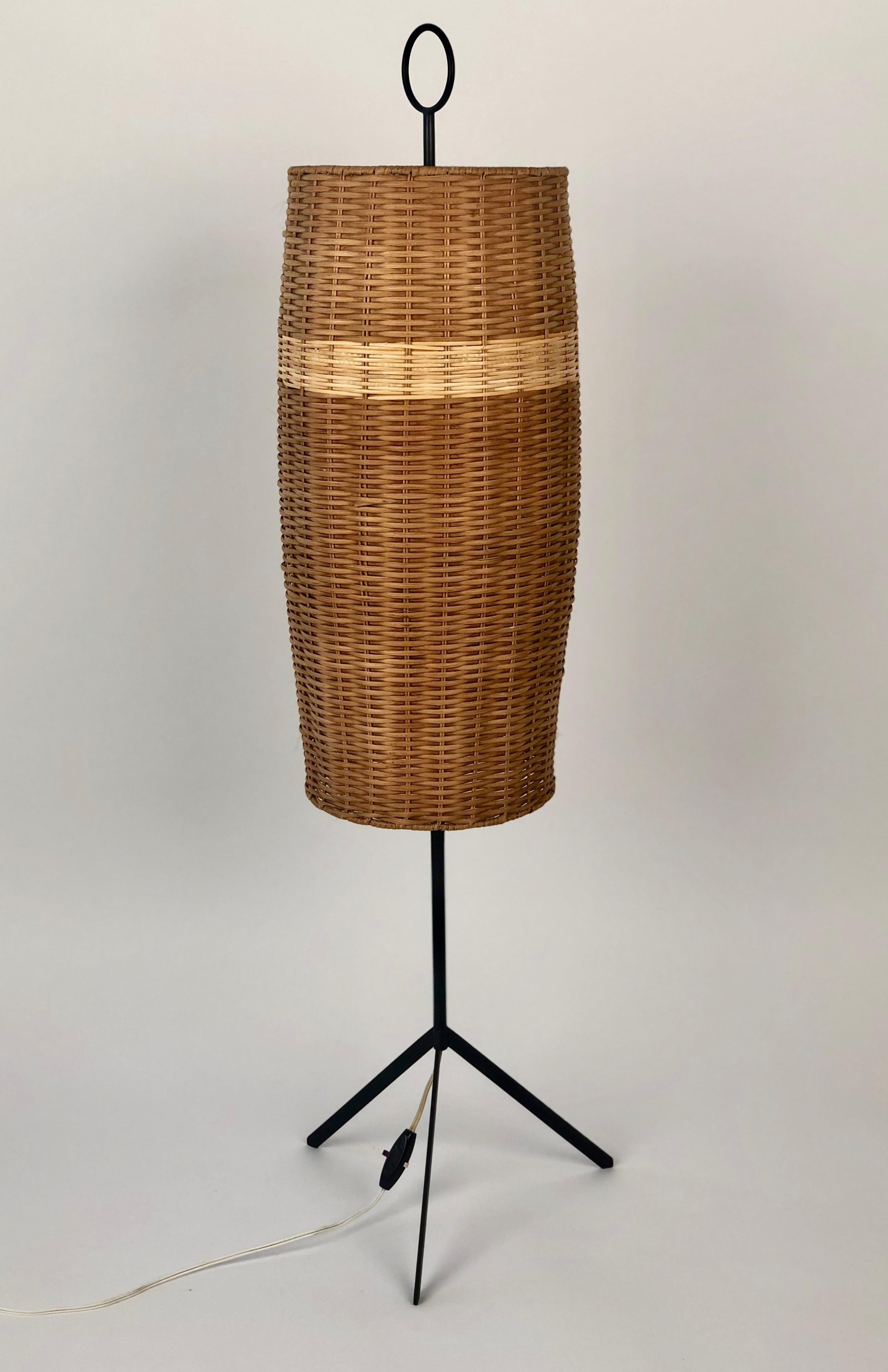 A rare Austrian mid-century floor lamp from J.T. Kalmar, manufactured around 1960.
 It features a tripod iron base at the bottom and a iron ring at the top.
The original woven wicker cane shade had some missing pieces , do to the rarity
of the lamp,