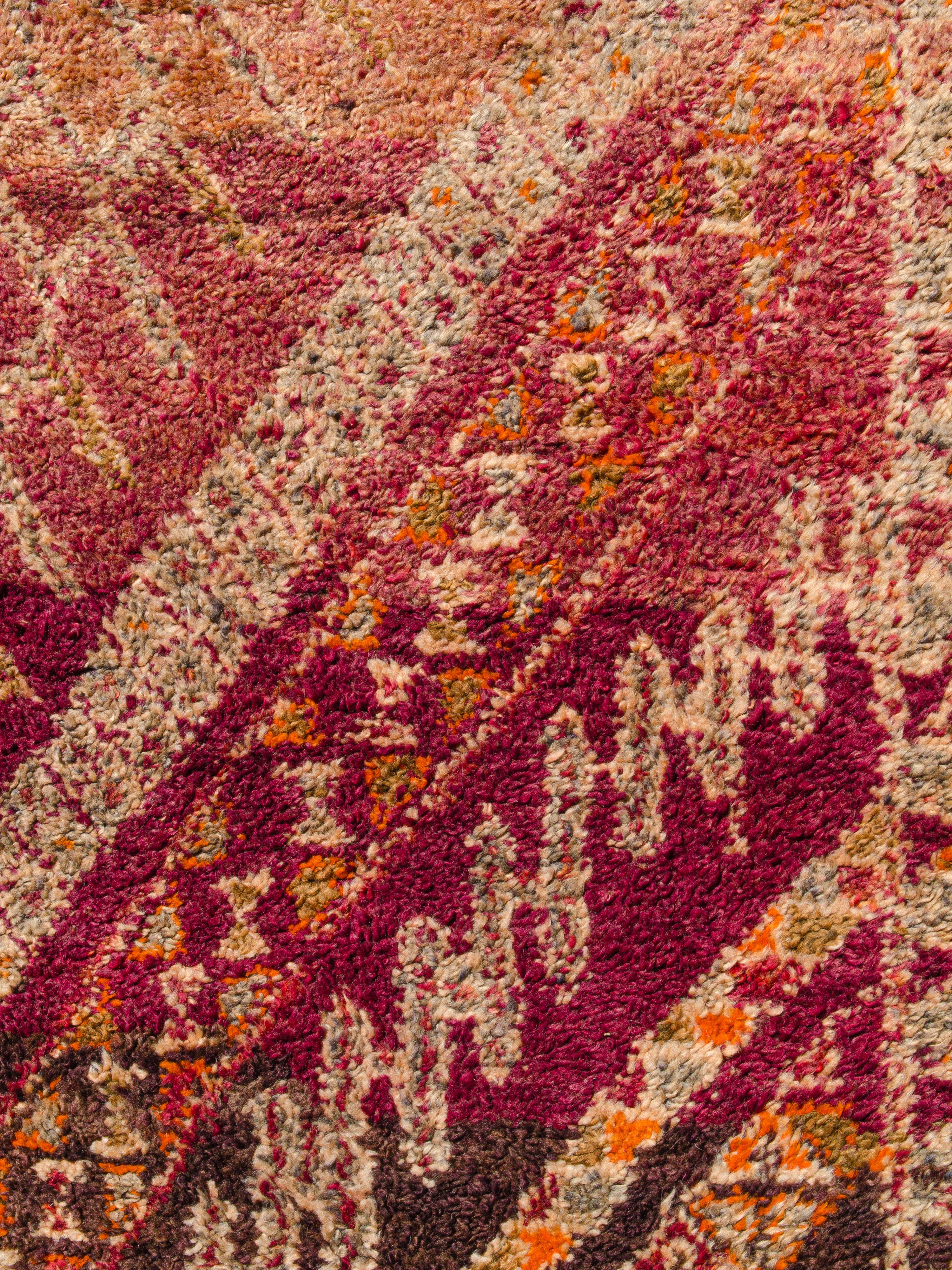 This vintage Moroccan Beni M'Guild displays a repeating series of large scale chevrons comprised of Berber motifs on an abrashed ground. Chains of triangles form protective borders along both selvedges. Knotted in an autumnal palette of burnt red,