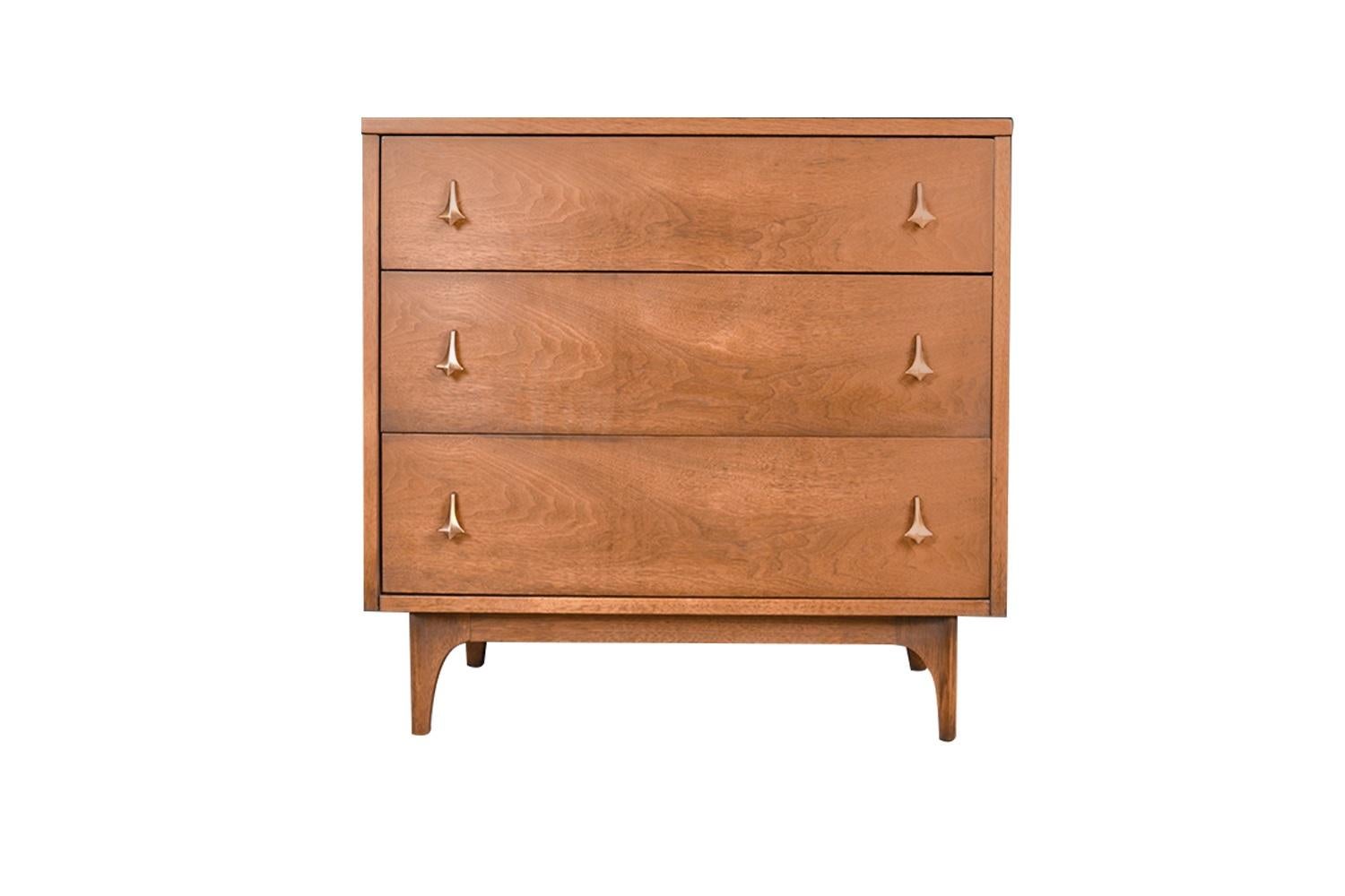 Fabulous Mid-Century Modern dresser three drawer bachelor chest circa 1960s by Broyhill Brasilia. Featuring a solid, beautifully grained walnut wood case and frame, housing three drawers each is adorned with original teardrop brass pulls, creating a
