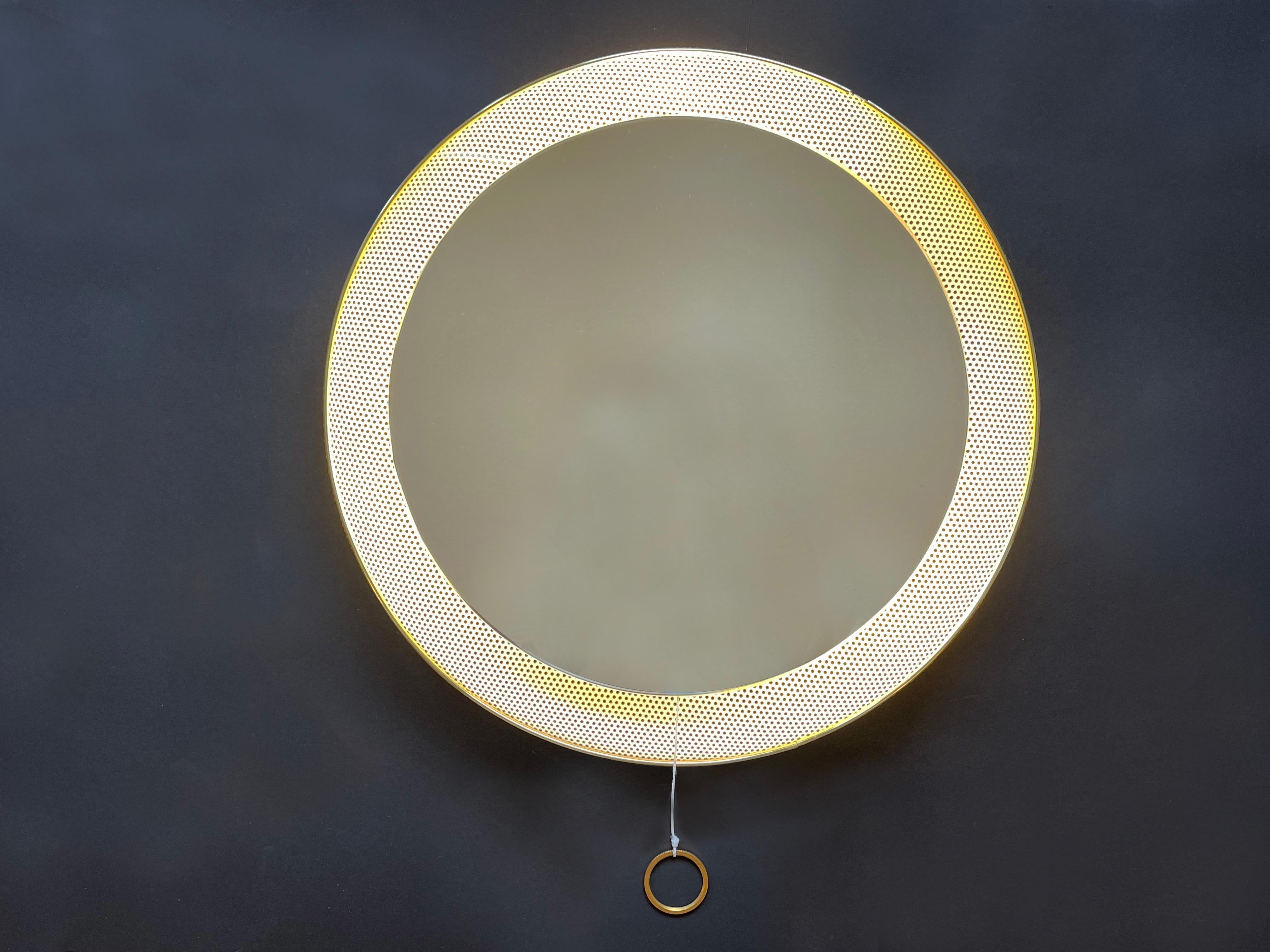 Mid-Century Modern round shaped wall mirror in white perforated metal back with golden rim.
Attributed to French designer Mathieu Matégot, 1950s to 1960s.
A beautiful design classic of the time, lit in the back with three E14 screw