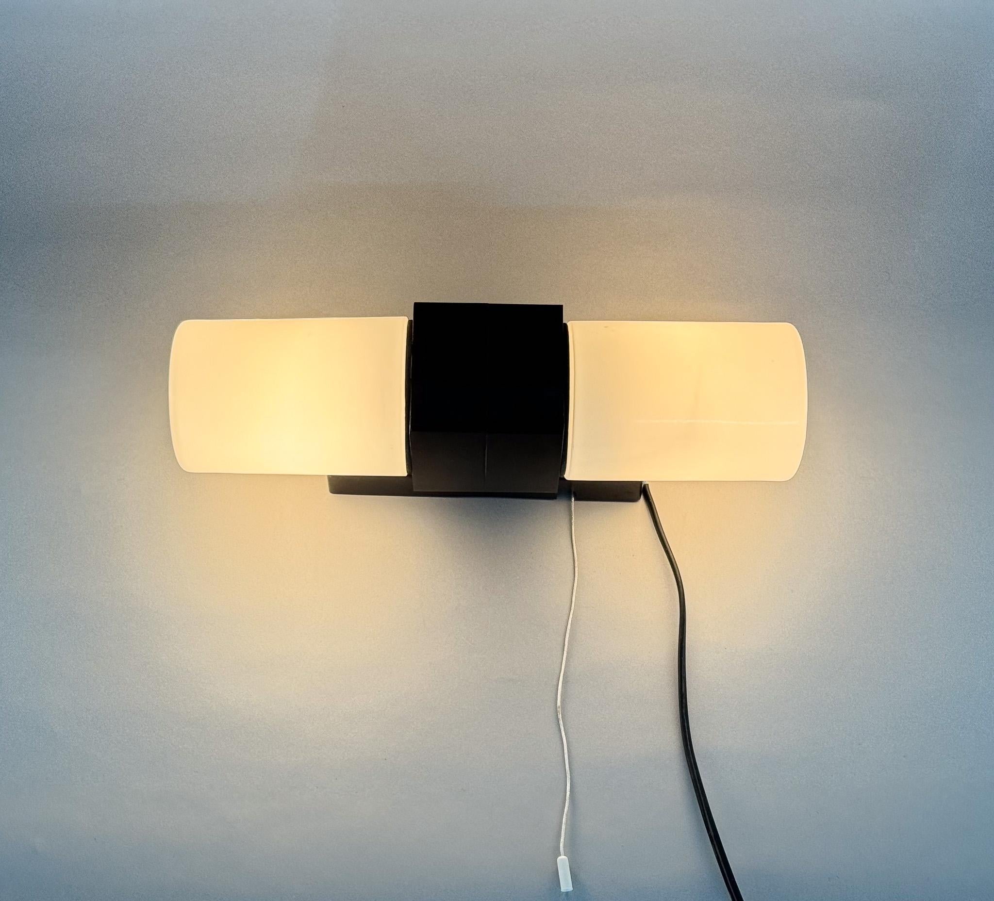 Designed in the 1950s in former Czechoslovakia as bathroom light above a mirror with a cord switch. Bakelite holders and opal glass shades. Seal rubber against moisture. Bulbs E14-E15, 2x40W. US compatible cable.