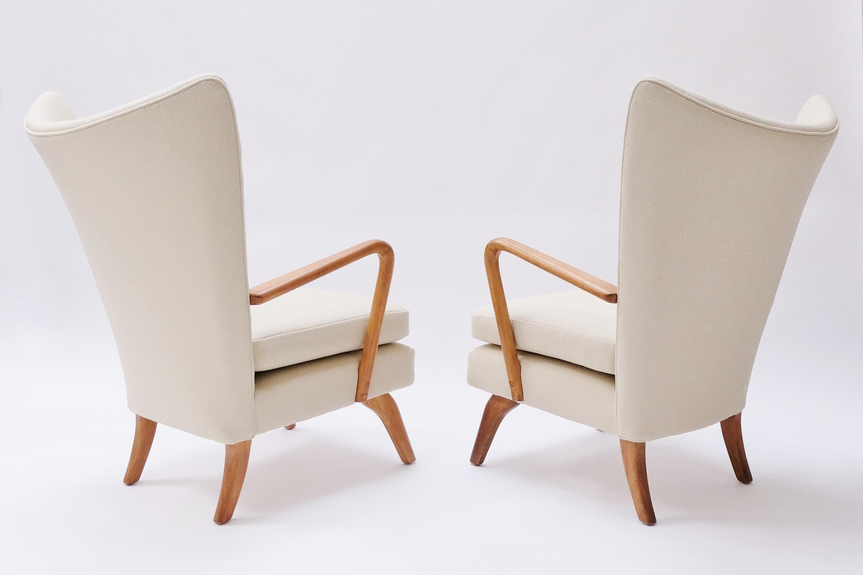A pair of highly collectible midcentury Bambino wingback armchairs designed by Howard Keith for HK furniture. England, circa mid-1950s.

These stunning armchairs feature a beautifully curved winged back with tufted button detail and honey-colored