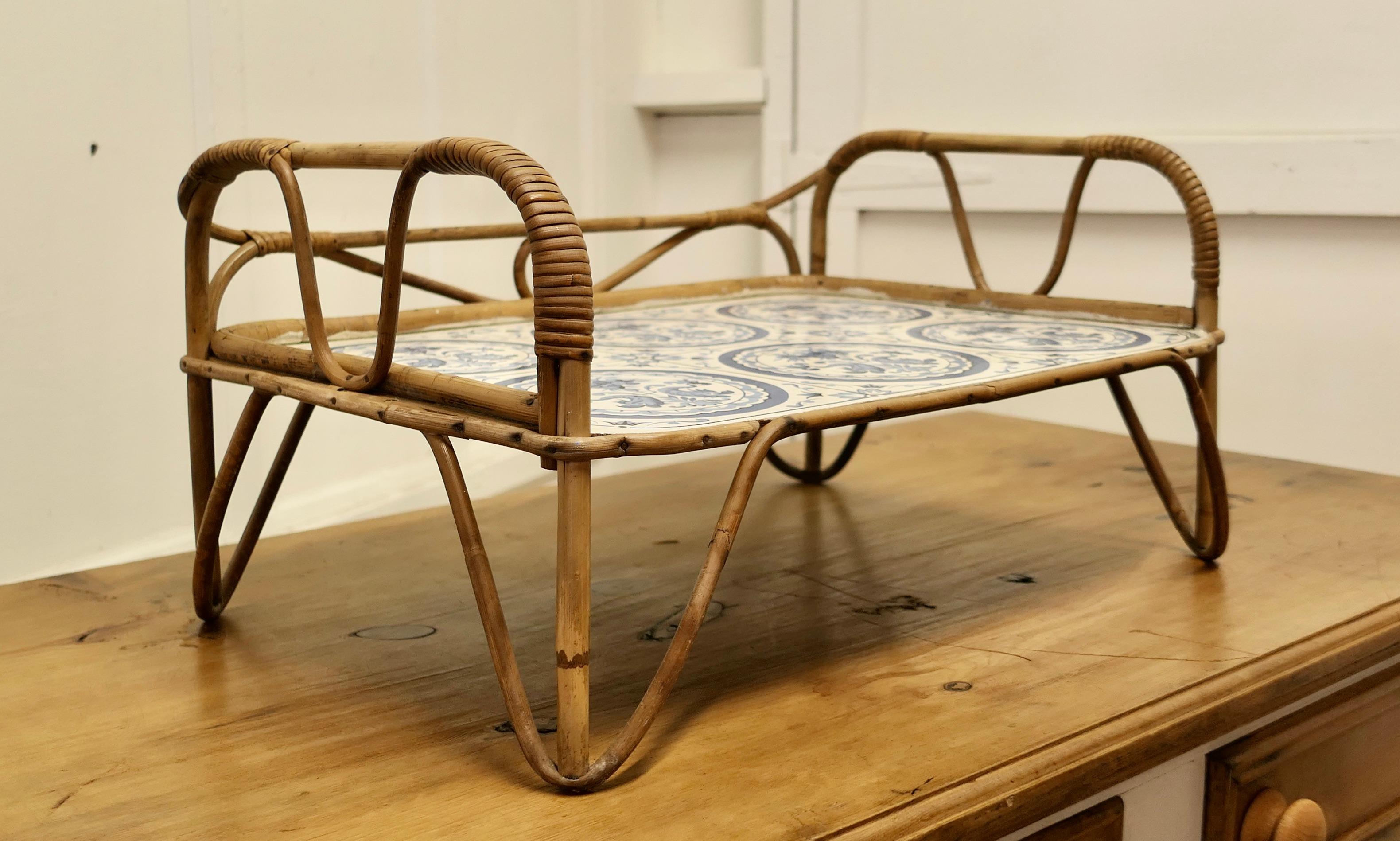 Mid-century bamboo and simulated delft bed tray.

A lightweight and very useful tray that sits over your lap for food and drinks or for reading 
The main body of the tray is made in bamboo and the table top is parchment paper in a blue and white