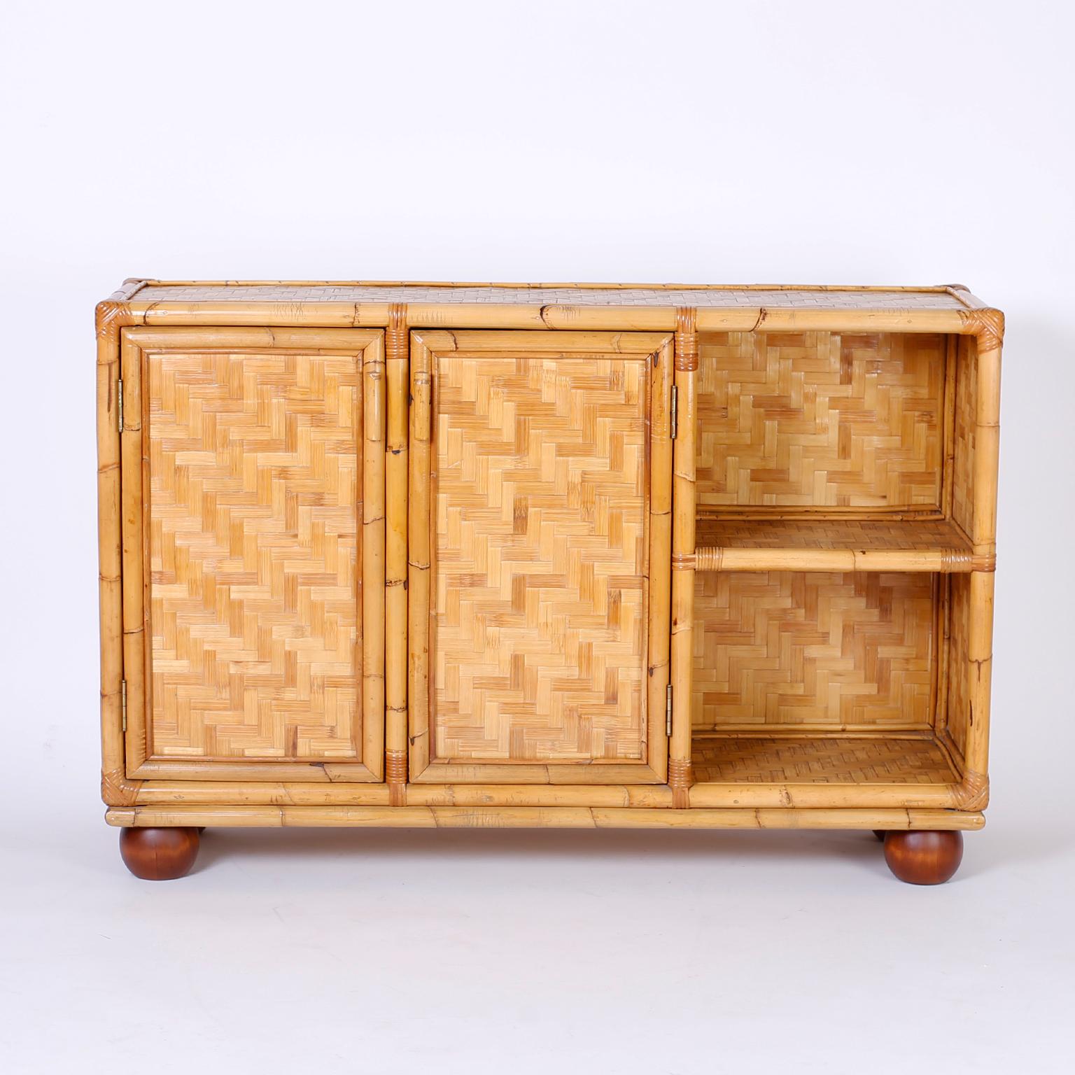 Unusual asymmetrical server featuring a bamboo frame wrapped at the corners with reed. The bar is complete with herringbone bamboo panels throughout, bun feet, and plenty of storage.