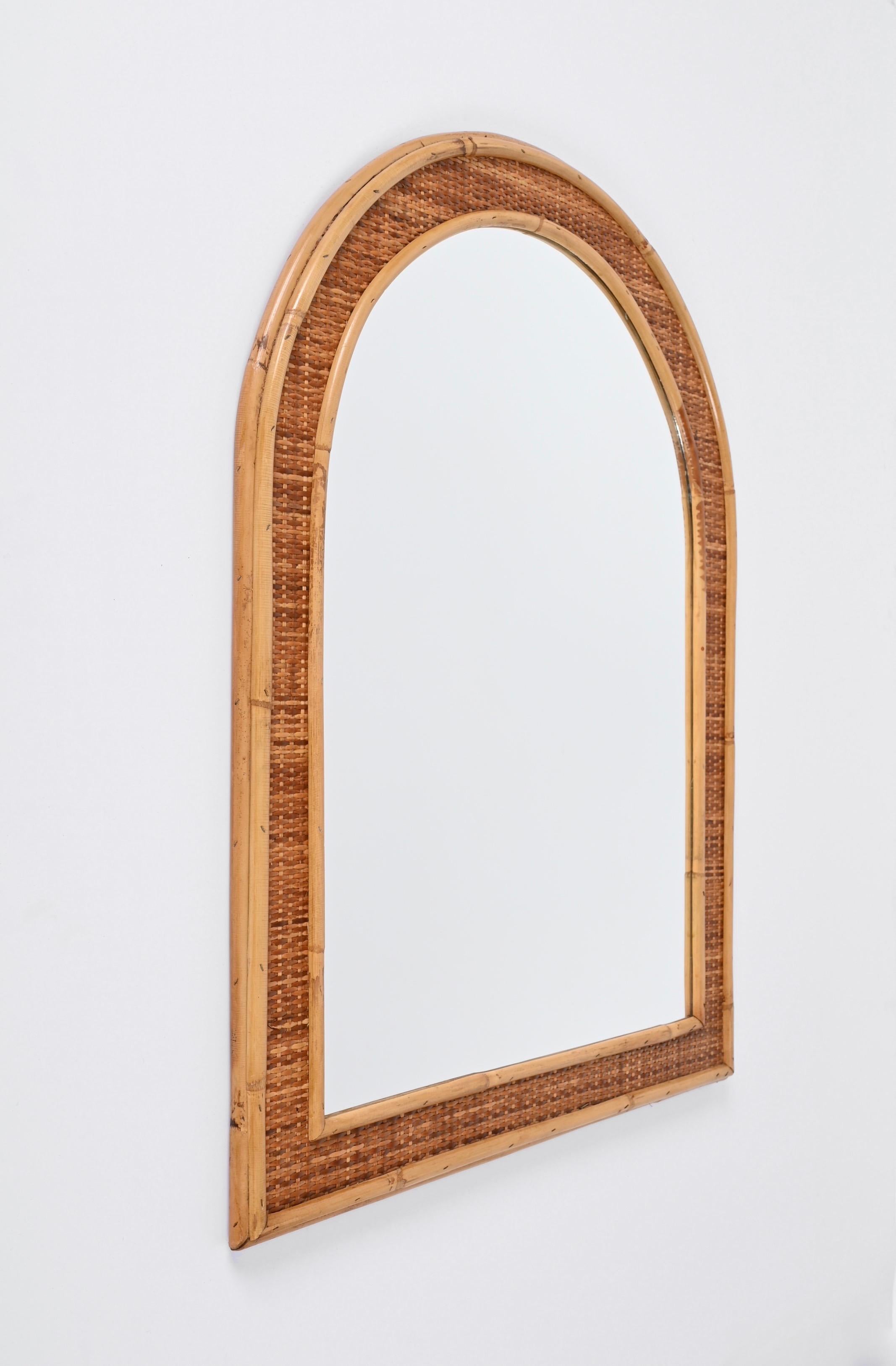 Spectacular mid-century arch shaped mirror in bamboo and woven wicker. This outstanding item was produced in Italy in the 1970s.
This piece is incredible due to its complex structure: it has an inner frame in bamboo a central part decorated with