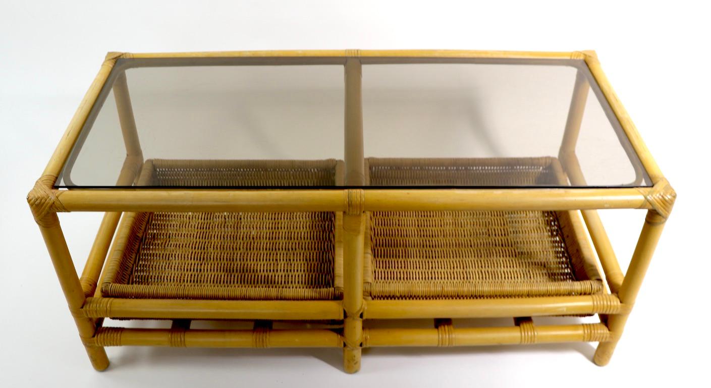 Good quality mid century coffee table with a bamboo frame, Formica top, removable two wicker trays, and a  tinted plate glass top. Well-crafted and in good original condition, clean and ready to use. Manufacture attributed to Ficks Reed,