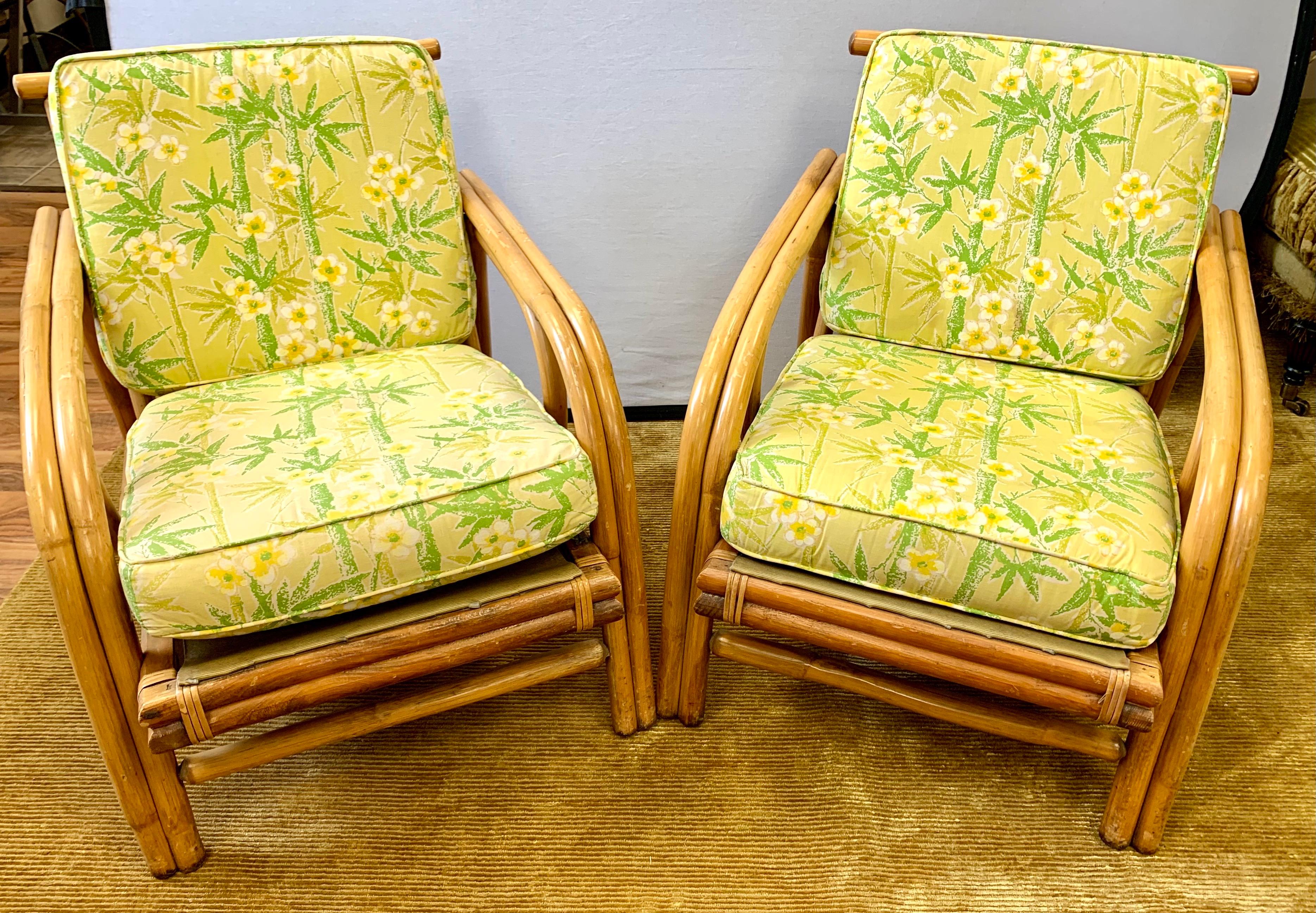 Pair of vintage midcentury bamboo rattan club chairs with original yellow and green tropical print upholstery. Structurally sound with e excellent craftsmanship on the bamboo frames.