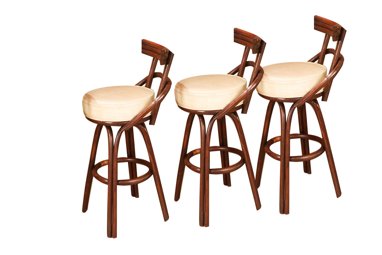 A set of three, midcentury, bamboo, rattan, Tiki, bentwood, swivel bar stools, in the style of Paul Frankl. Each with curved, bentwood, backrest and armrest. The swivel padded seats made of beautiful leatherette, Naugahyde raised on a high double