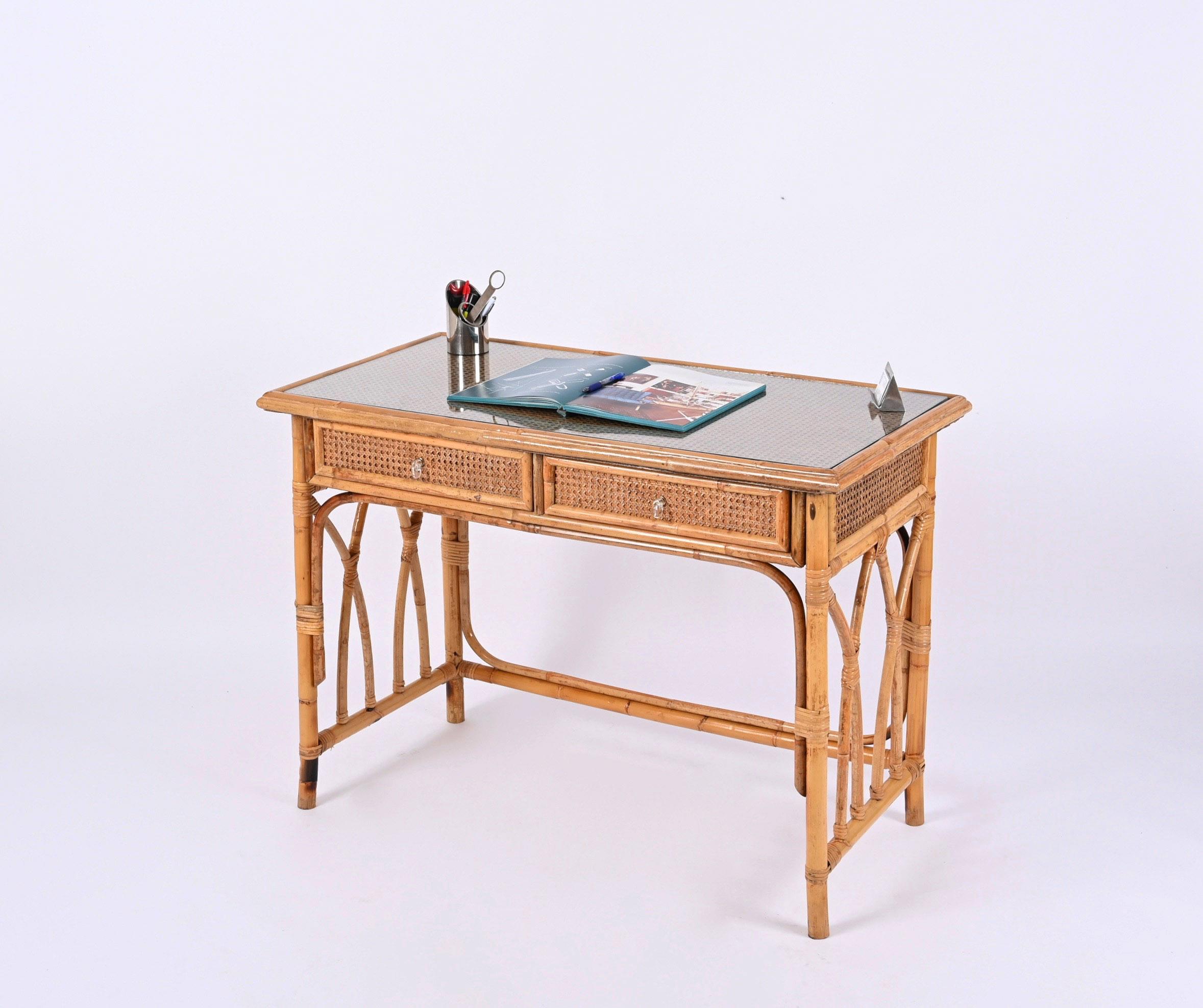 Fabulous mid-century desk in bamboo and Vienna straw wicker with crystal top. This unique piece was designed in Italy during the 1970s.

This outstanding desk features a structure in curved bamboo cane and rattan decorated on all the sides and on