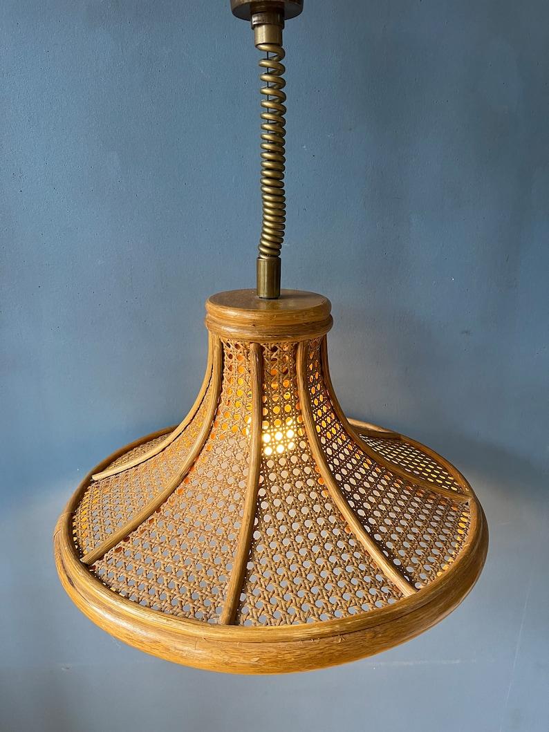 Big mid century rotan boho pendant lamp. The 'boho' style light fixture has a nice decorative pattern through which the light escapes. The height of the lamp can easily be adjusted with the rise-and-fall system. The lamp requires one E27/26