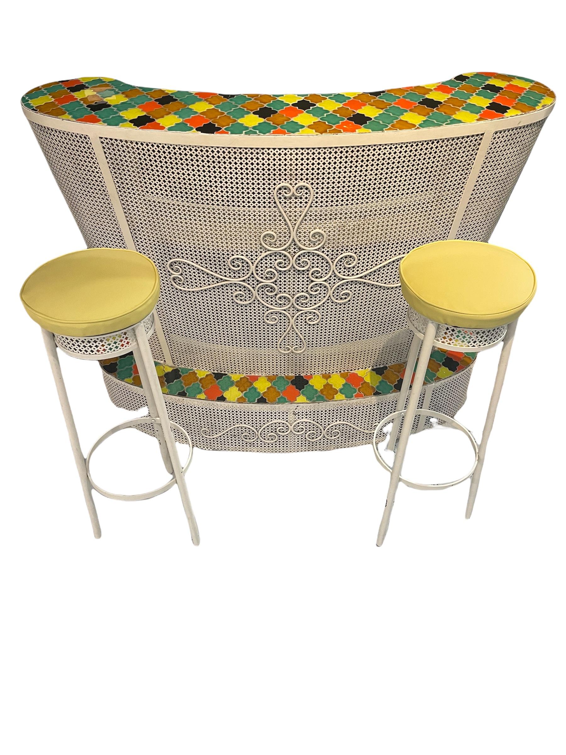 Un bar et un tabouret du milieu du siècle en fer et des carreaux de céramique colorés en arlequin donnent à ce bar le parfait style Hollywood Regency.

Tabouret rembourré en cuir jaune.