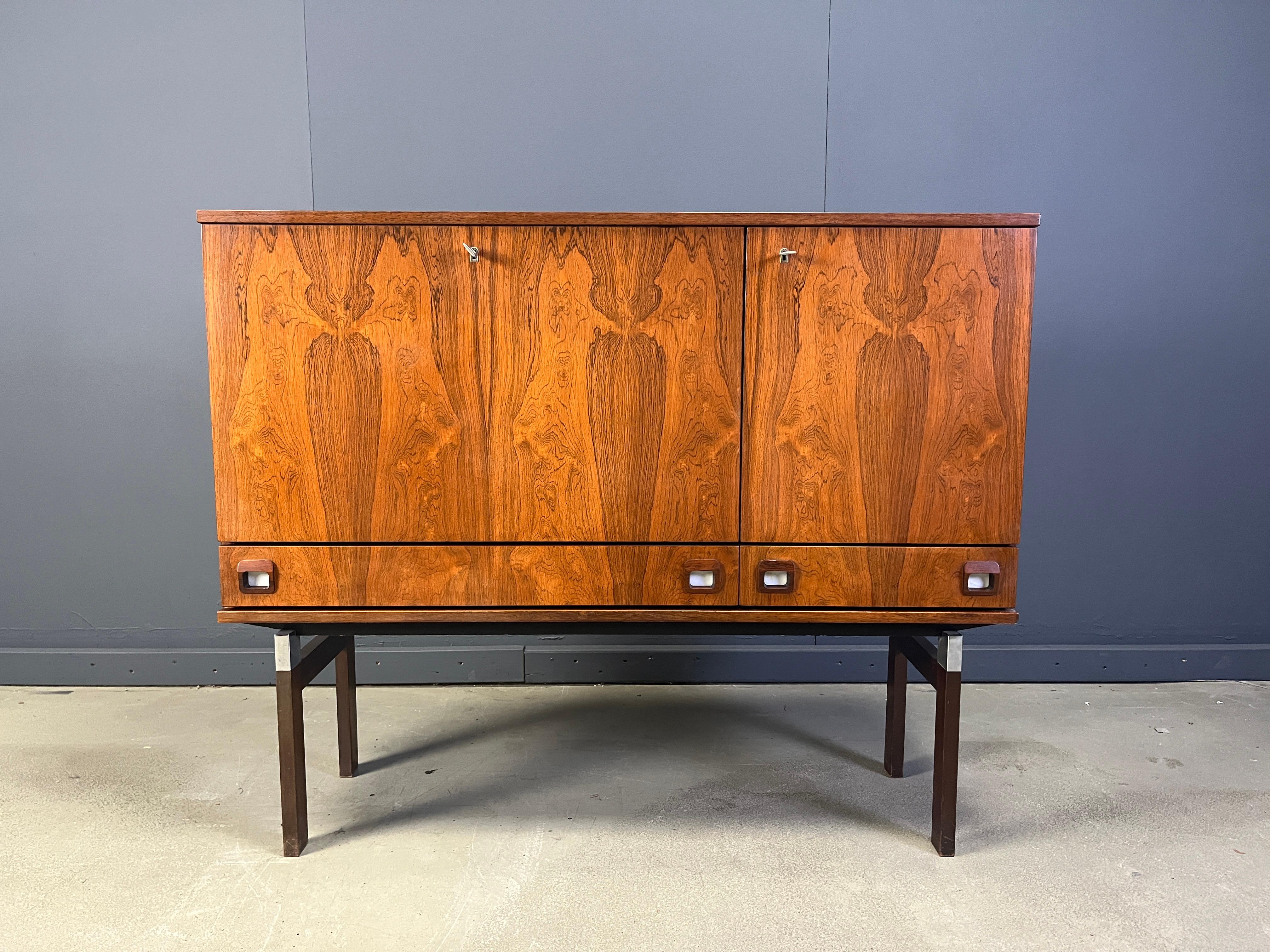 Bellissimo mobile bar/tavola alta di metà secolo di Fristho con splendidi pannelli in legno.

Composto da un'anta ribaltabile che rivela uno scomparto per il bar e un ulteriore spazio di archiviazione e da due cassetti, l'armadietto offre molto