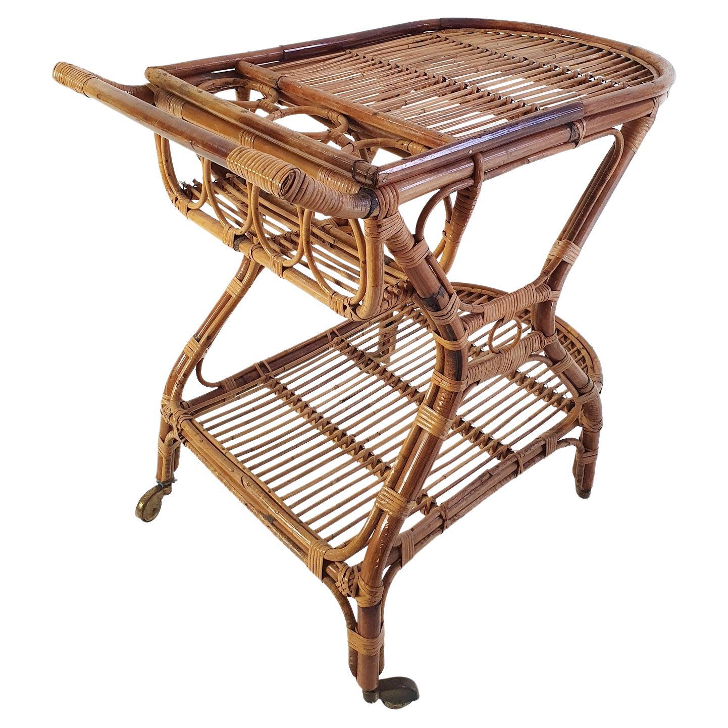 An Italian two tiered bar cart from the 1950's made from bamboo and rattan. The bar cart has holders for four bottles in total. Retains the original castors and has an overall nice condition with the original patina. All original without