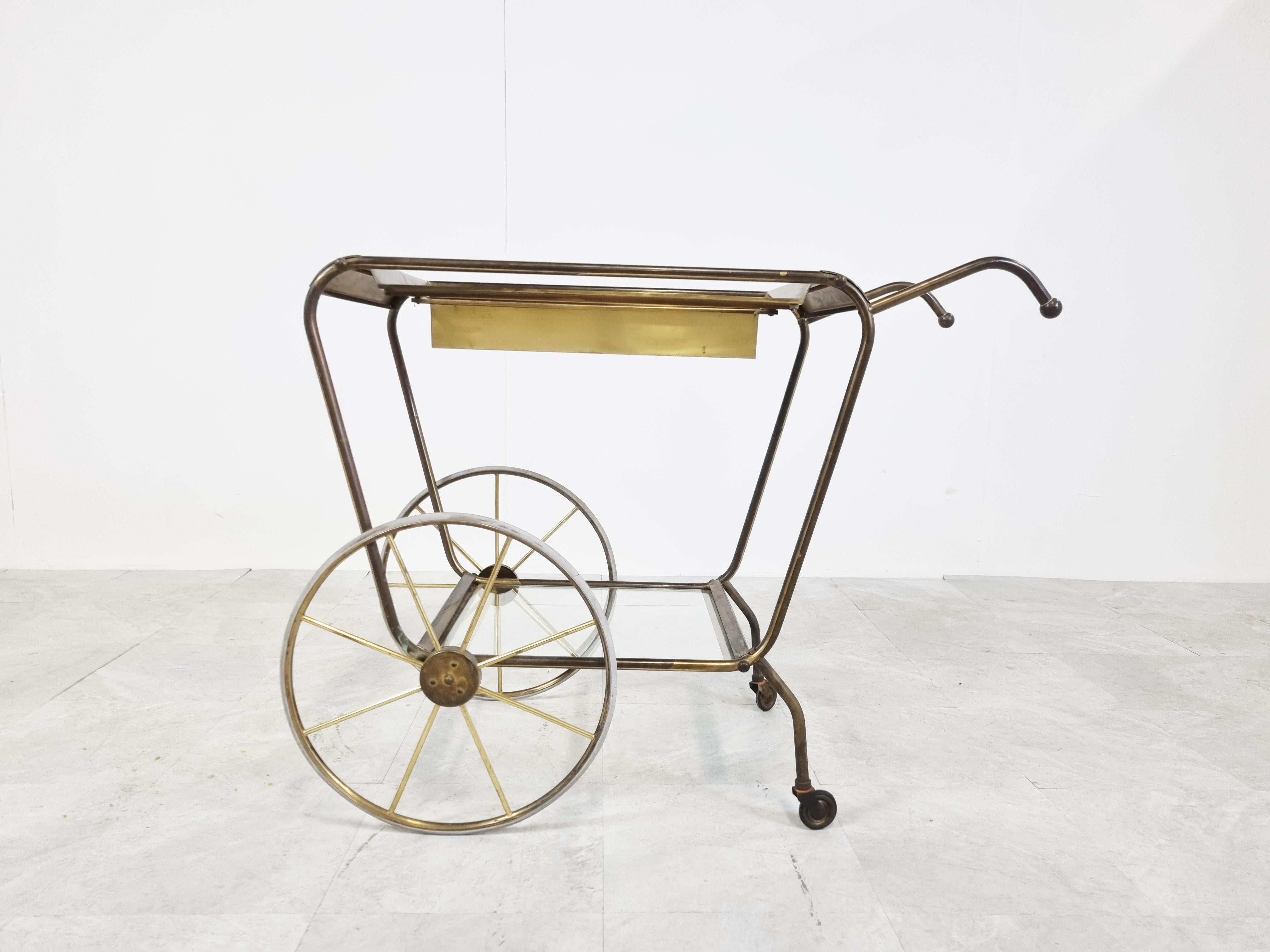 Very elegant and beautifully patinated brass bar cart or serving trolley very much in the style of Josef Frank.

It has an integrated bottle holder and glass shelves.

Still rolls smoothly after 70 years

1950s- France

Good condition with