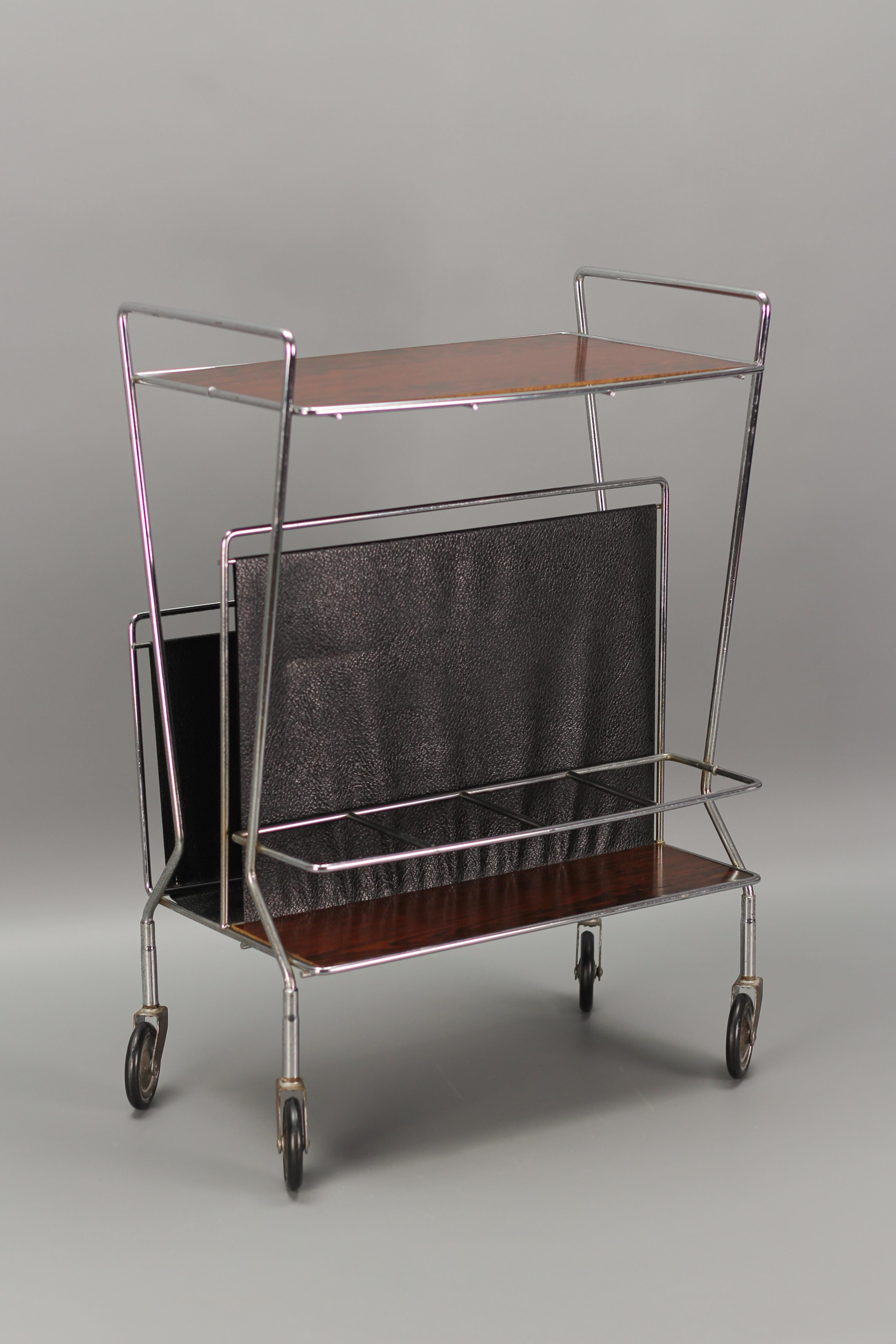 Mid-Century Modern bar cart, trolley, or side table, Germany, 1970s. This elegant vintage bar cart features a chromed metal frame, one top shelf, a compartment for magazines, and storage for bottles. 
Dimensions: height: 60 cm / 23.62 in; width: 47