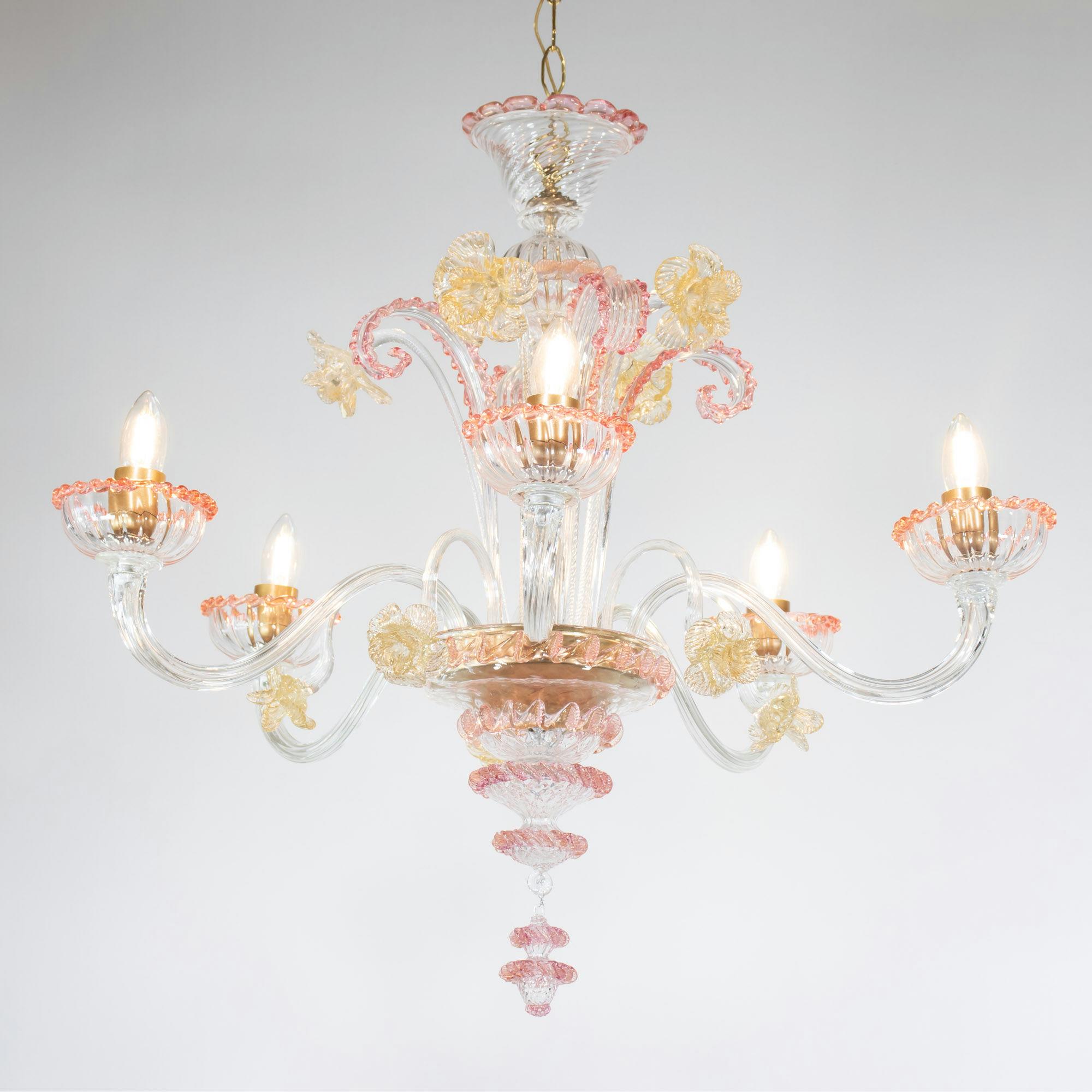 This pastel pink and gold handcrafted gold-infused Cristallo Murano chandelier has five undulating arms with pink rigaree trimmed bobeches. The chandelier is adorned with two levels of gold infused glass daffodils, with additional pink trimmed