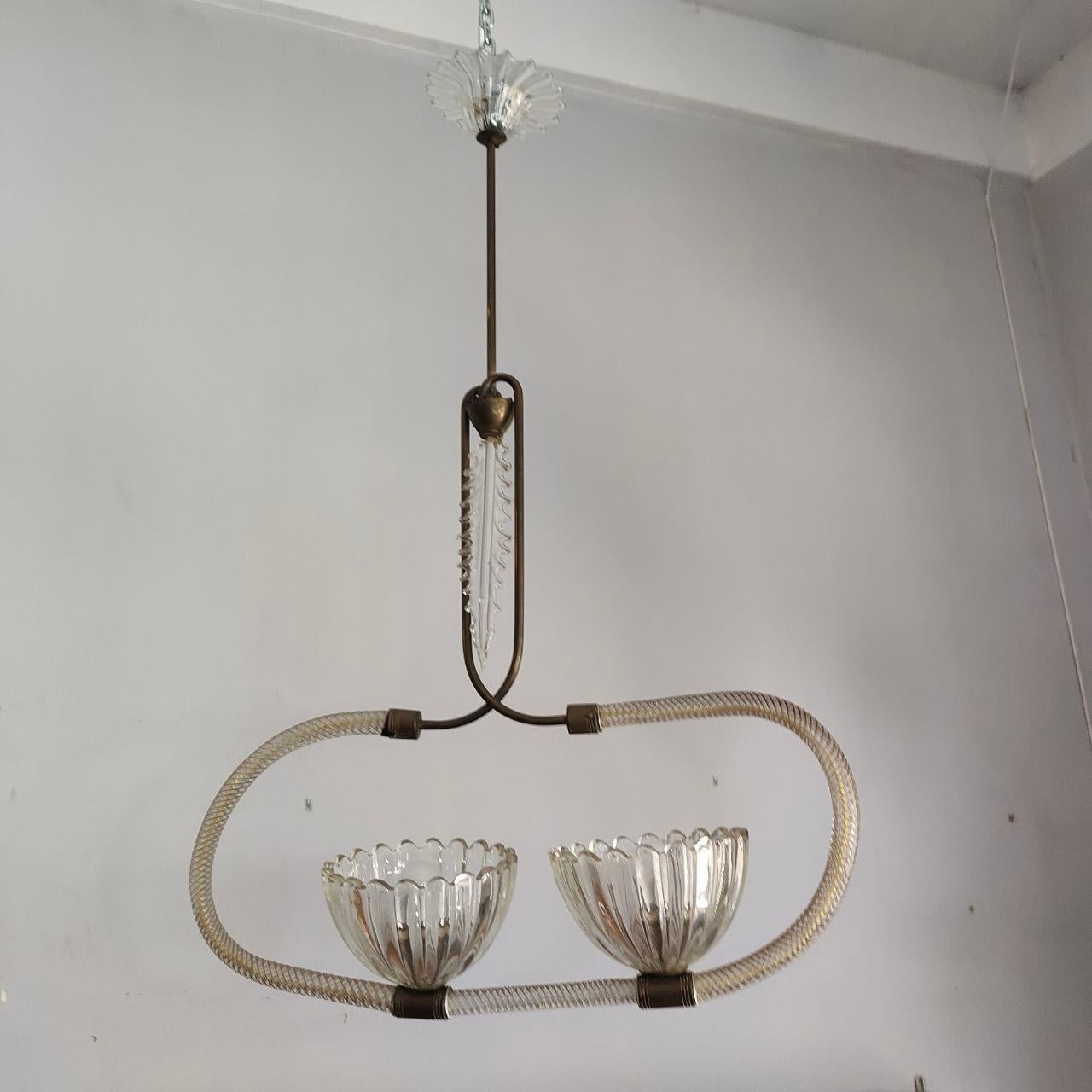 Cet élégant lustre raffiné, fabriqué à Venise vers 1940, est attribuable à Barovier&Toso. Son cadre ovale est façonné à partir de cannes de verre de Murano gracieusement courbées et torsadées, chaque élément étant soufflé à la main pour créer des
