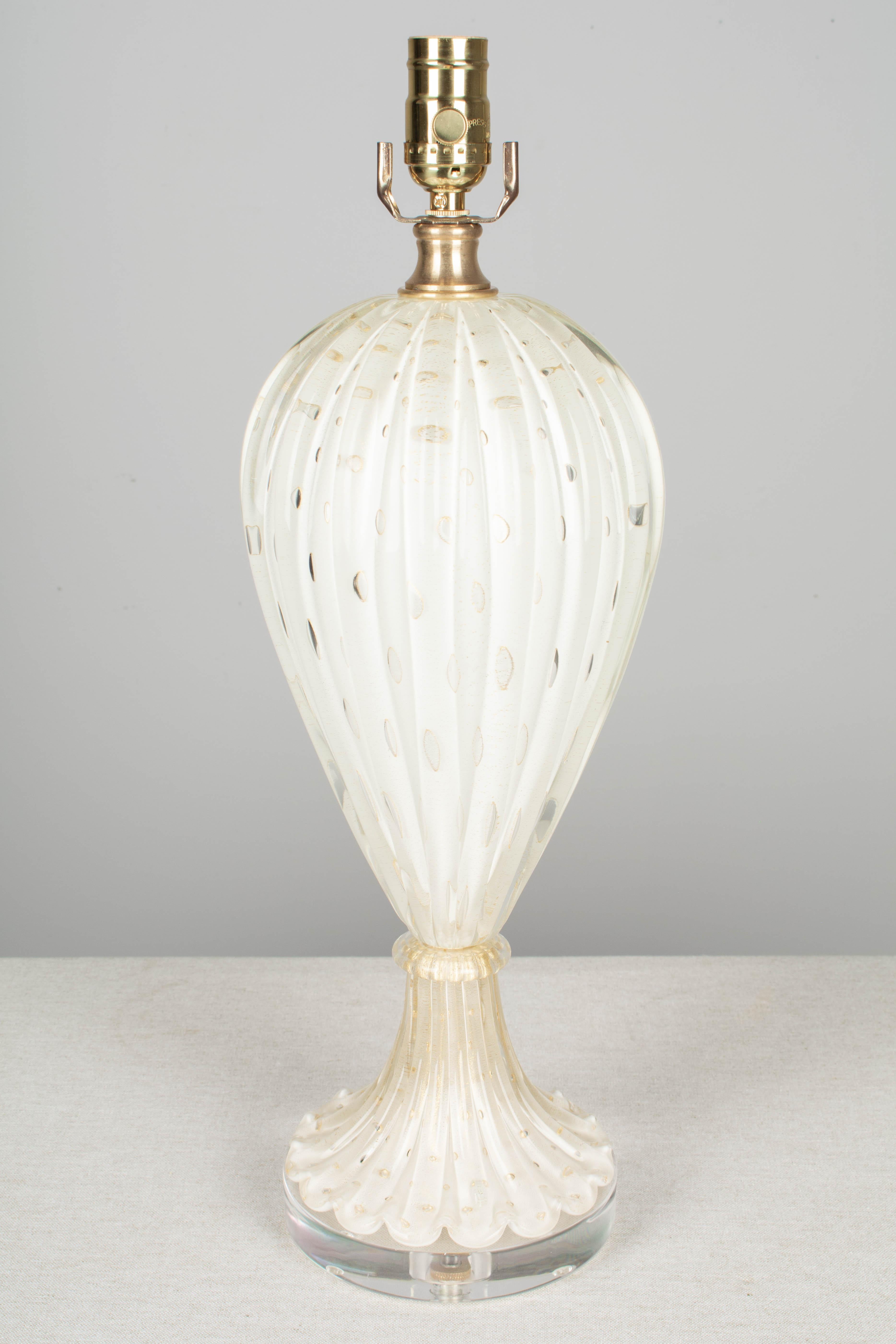 A midcentury Murano glass lamp by Barovier & Toso. White cased hand blown glass with real gold leaf inclusions in the controlled bubbles. Tall elegant shape with ribbed form. Rewired with new socket and cord. New 1