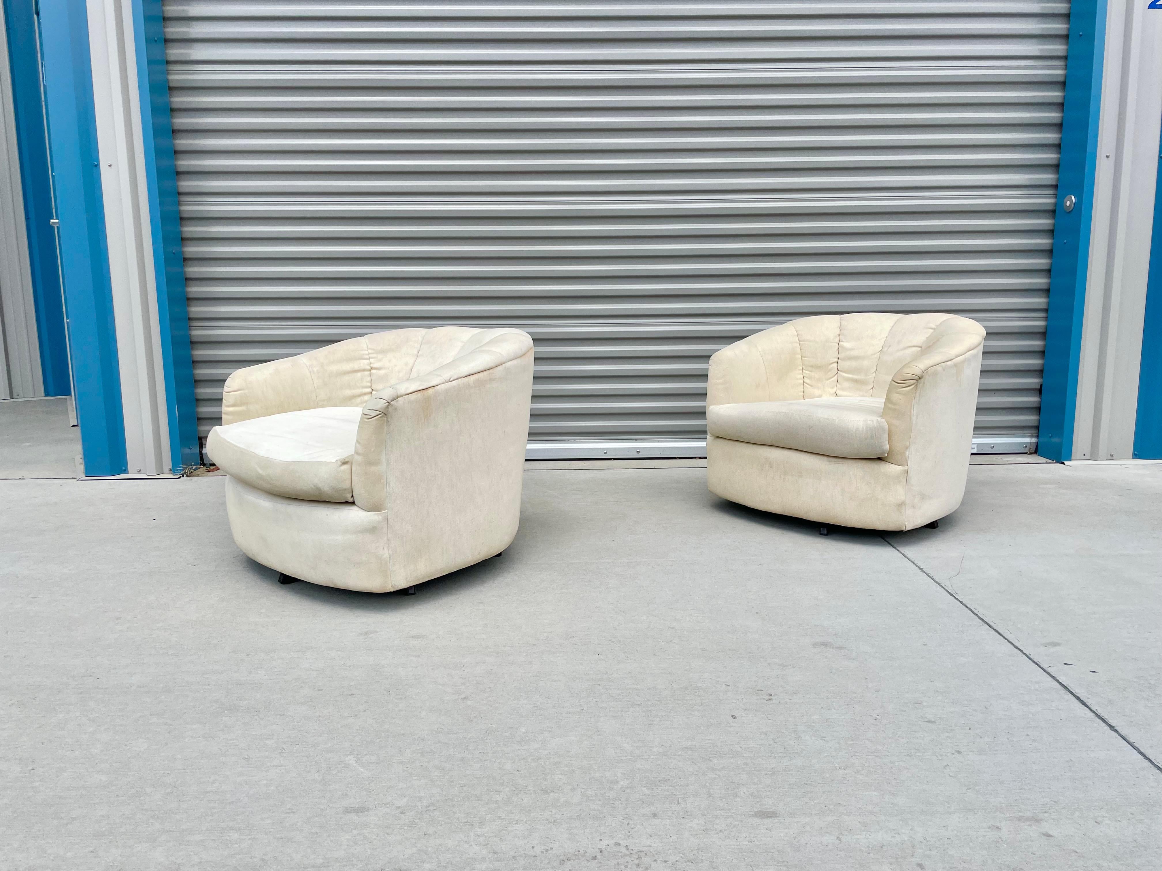 Fantastic vintage pair of barrel chairs styled after Milo Baughman designed and manufactured in the United States, circa 1970s. These beautiful chairs feature a swivel base that rotates 360 degrees. The chairs have a white fabric upholstery that
