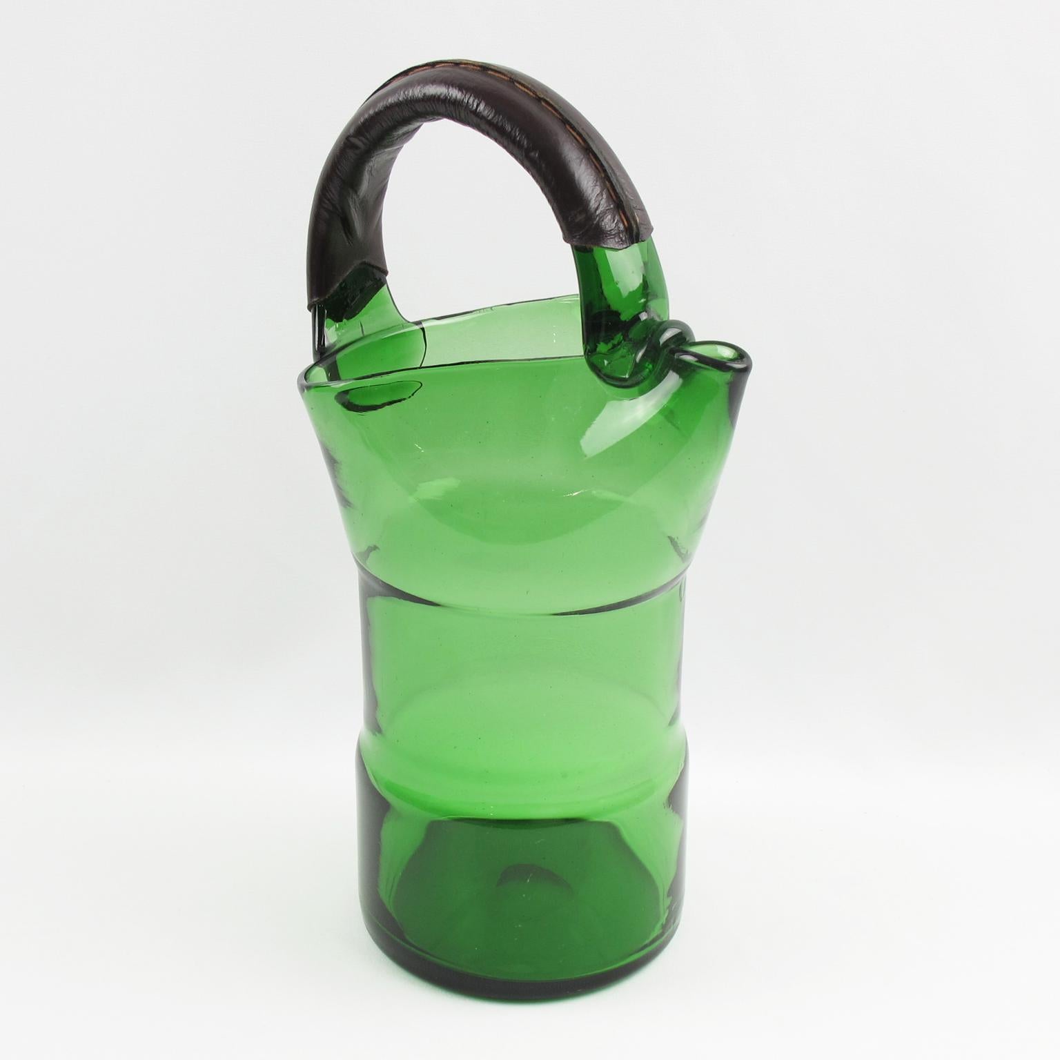 This is a stunning Italian mouth-blown glass cocktail pitcher crafted in the 1960s. This lovely green glass mixer jug is accented with a dark brown hand-stitched leather handle and is perfect for barware use and serving lemonade or water. A polished