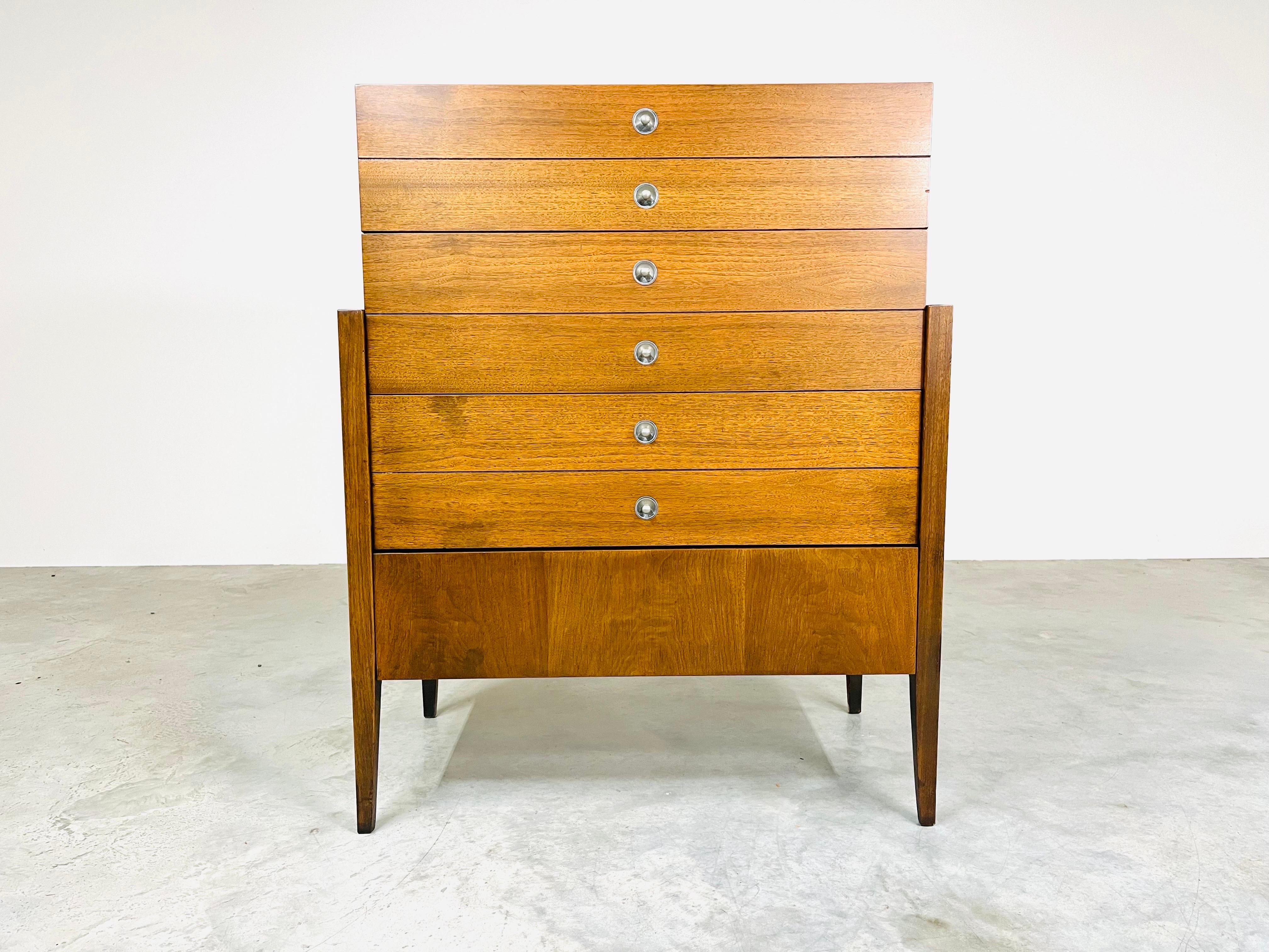 Seldom seen tall dresser in walnut having 4 deep drawers with ample storage and Paul McCobb style drawer pulls. Stunning lines for this case designed to appear as though it’s set on a tapered leg support frame. 
Bassett Circa 1960
In excellent