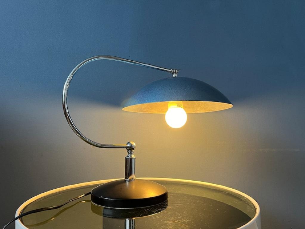 Beautifully shaped mid century desk lamp with chrome frame and blue shade. The lampshade can easily be adjusted and fixated with the chrome knob. The lamp requires one E27/26 (standard) lightbulb and currently has an EU plug (plug-converter can be