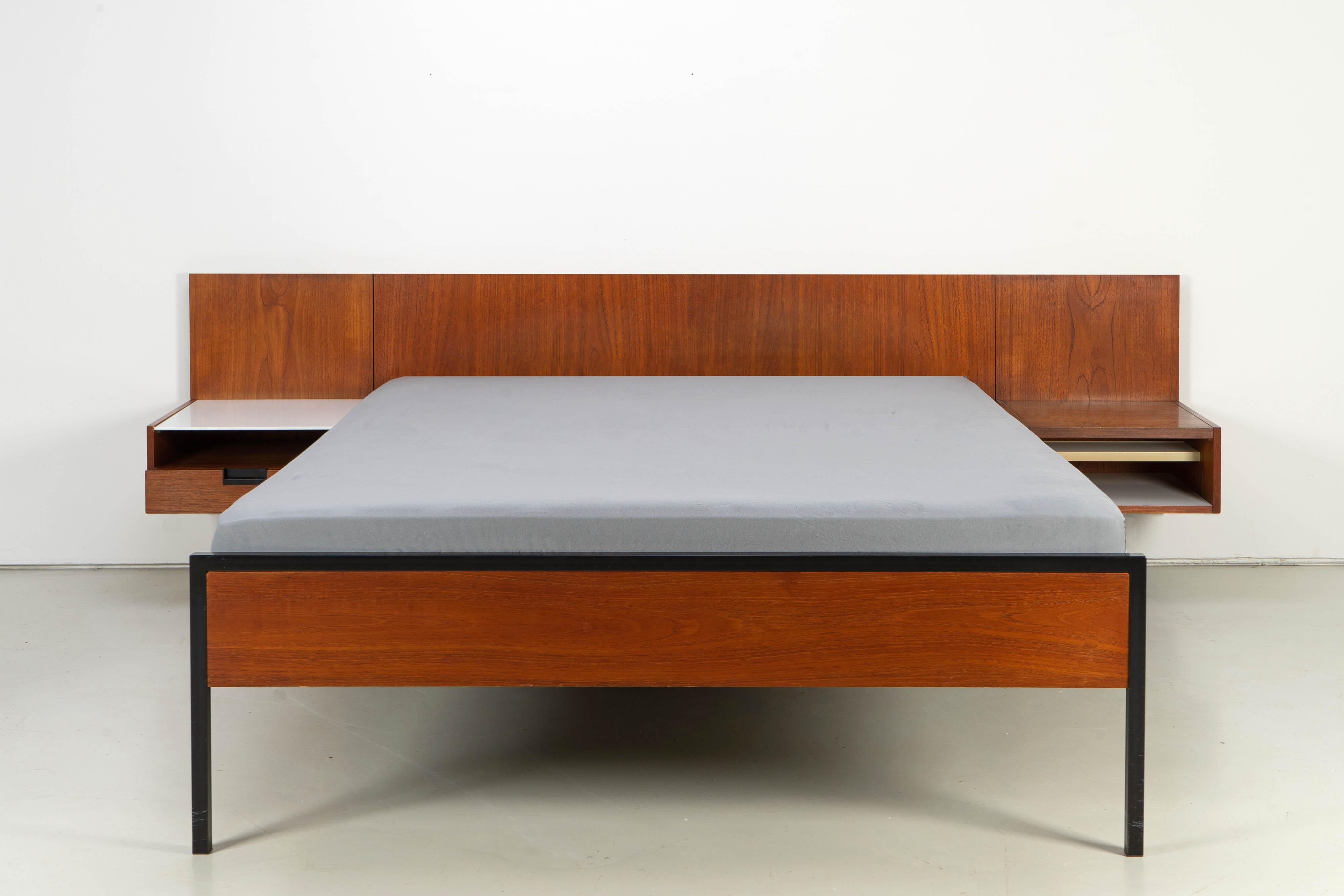 Rare vintage bed by Cees Braakman for Pastoe from the 1960s. This bed with headboard and two hanging bedside cabinets consists of a steel frame and wooden surfaces veneered with teak. One bedside cabinet has a drawer and a shelf made of white glass,