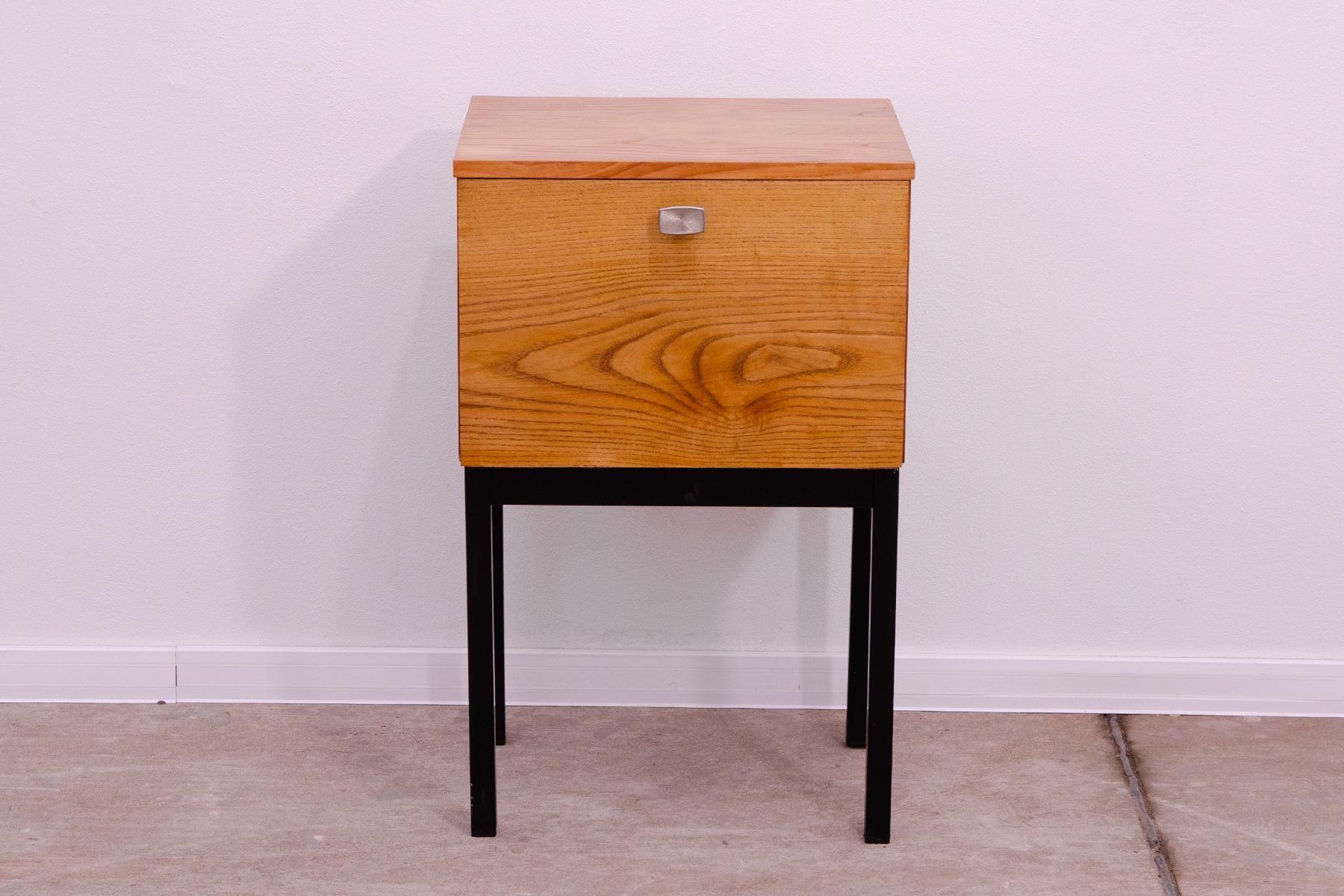 This stylish bedside table was manufactured by UP Závody in the former Czechoslovakia in the 1970s. It is made of ash and maple wood and plywood. It has iron legs.  It is in very good Vintage condition, with slight signs of age and use. UP Závody