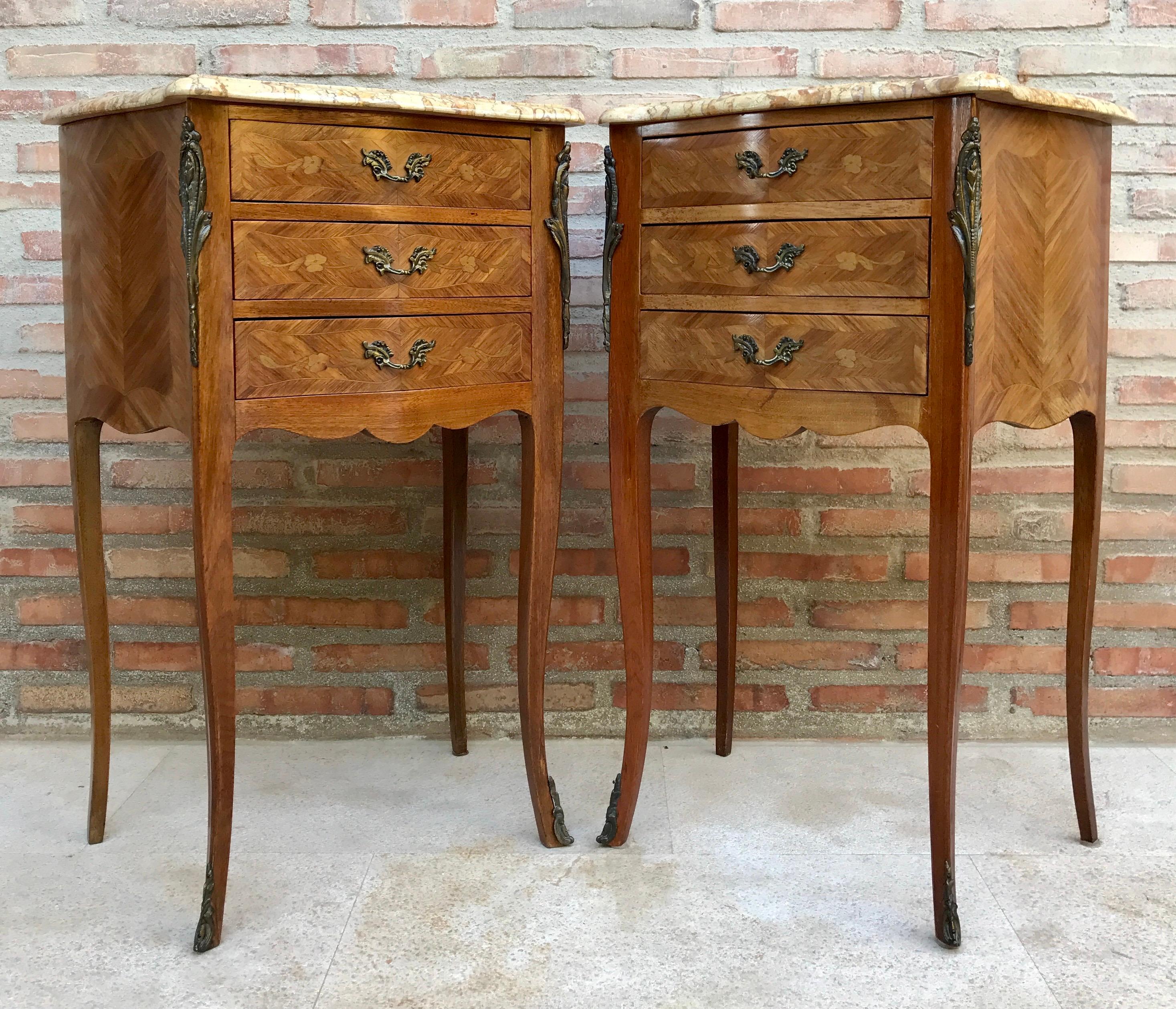 Pair of bedside tables or side tables or nightstands in French walnut with marquetry and marble top from the mid-20th century. 
A pair of fine French nightstands or walnut nightstands. Each one has a square top with a marble top and three drawers