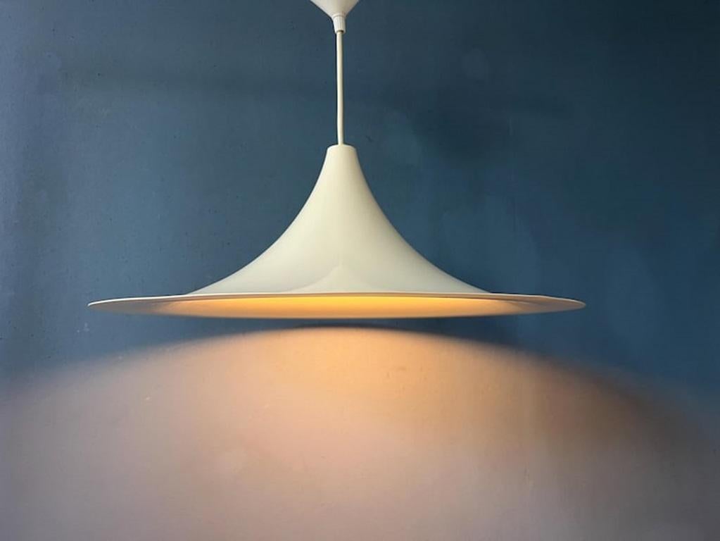 Lampada a sospensione a forma di cappello da strega di metà secolo, di colore bianco. Il paralume è in metallo ed è laccato in bianco/beige. La lampada richiede una lampadina E27 (E26).

Informazioni aggiuntive:
Materiali: Metallo
Periodo: