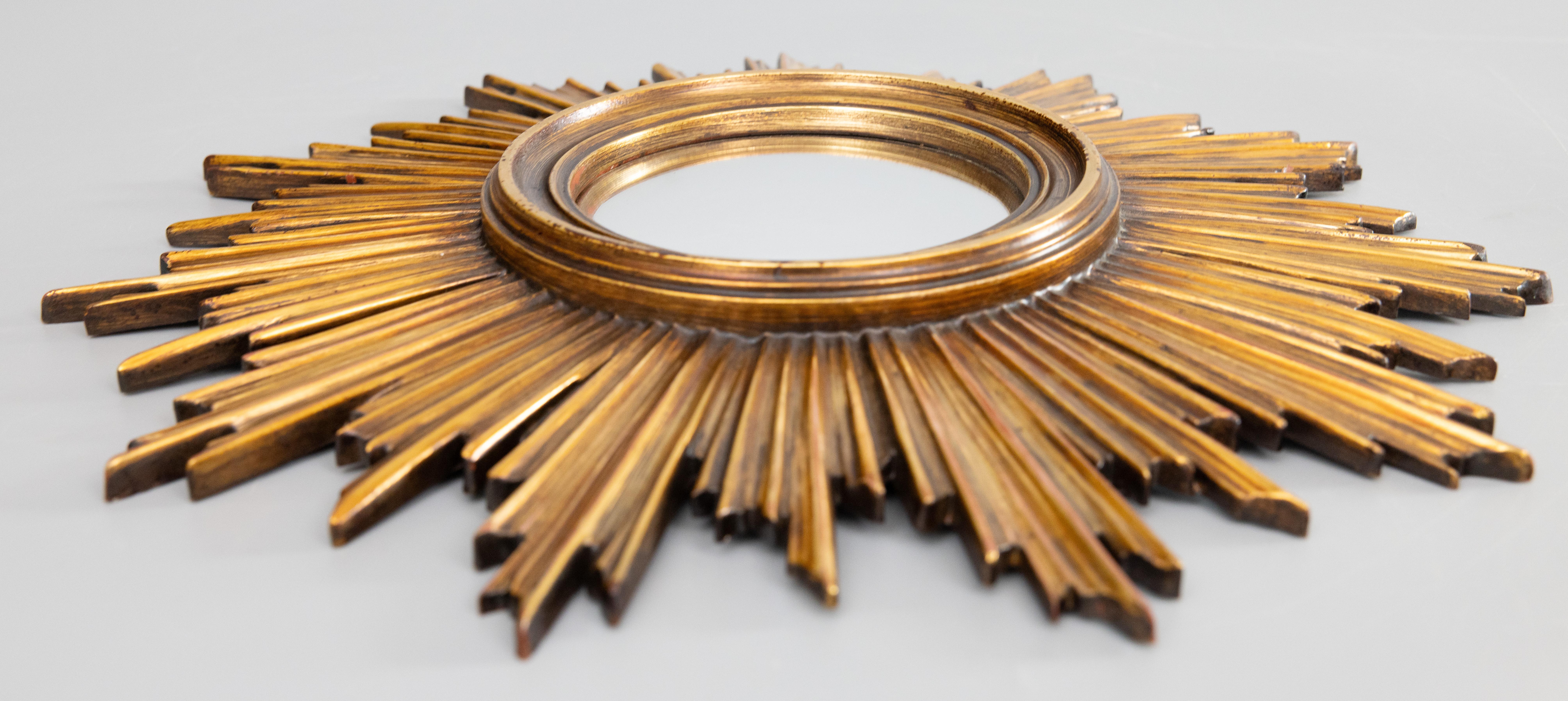 Superbe miroir en résine dorée à effet soleil de Deknudt, daté de 1968, datant du milieu du siècle dernier. Label du fabricant au verso. Il conserve le miroir convexe d'origine qui est entouré de jolis rayons de longueurs alternées avec une belle