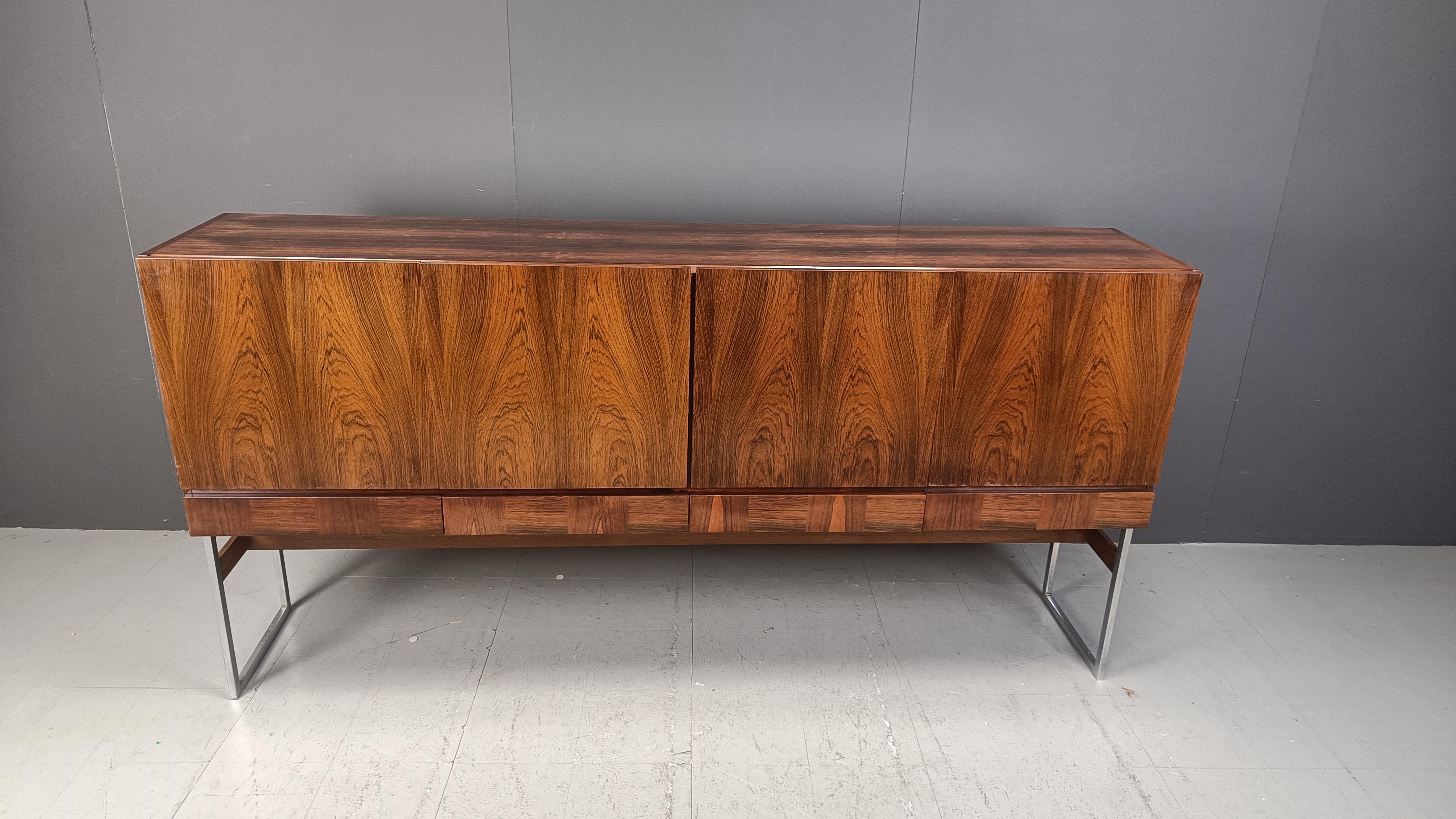 Buffet haut ou buffet du milieu du siècle avec un beau bois de placage et une base en chrome et en bois.

Le buffet se compose de 4 portes et de 4 tiroirs offrant un grand espace de rangement.

Très proche du style de Rudolf Calle, ce buffet a été