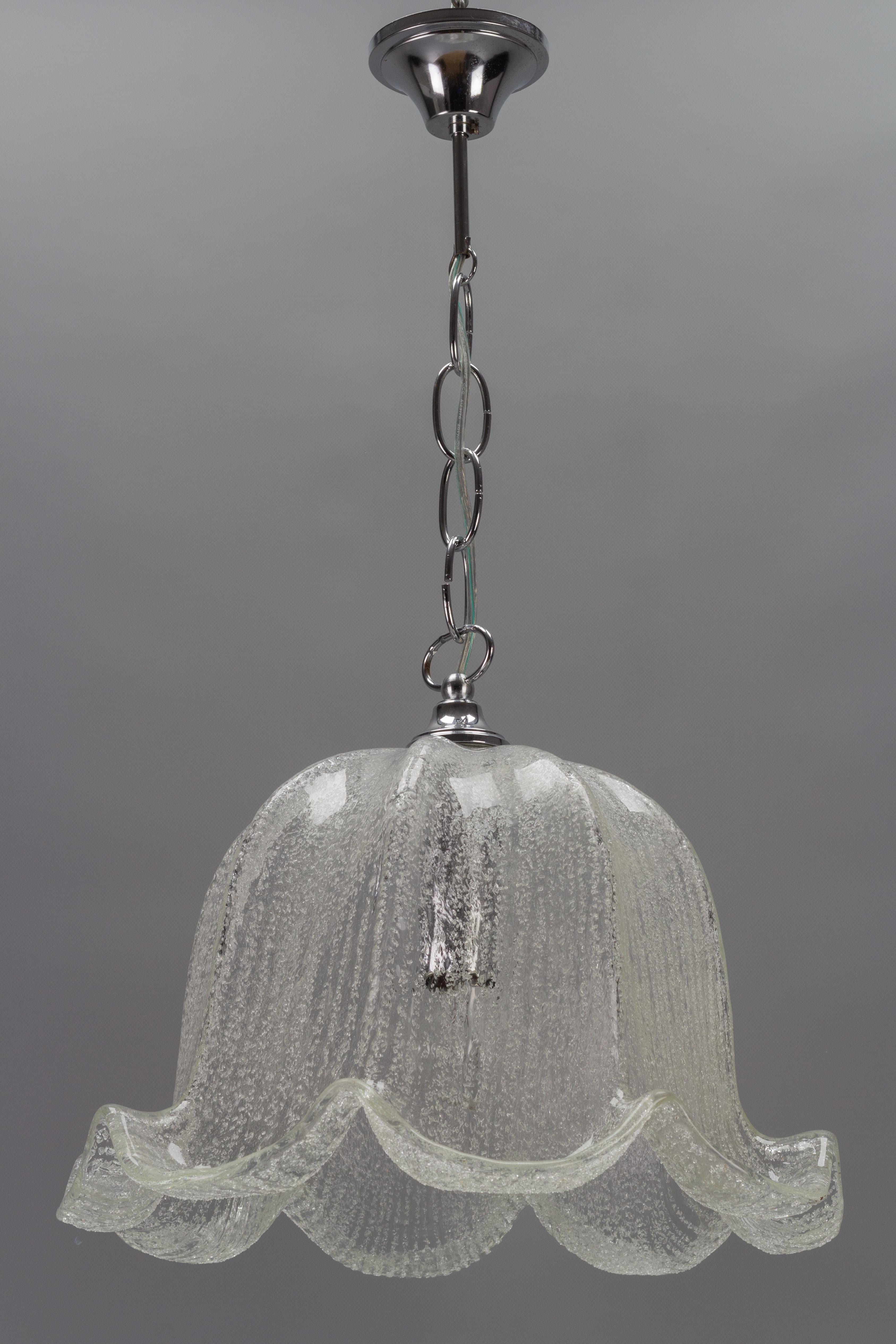 Eine elegante Mid-Century Modern Pendelleuchte mit schön geformtem Eisglasschirm und verchromter Metallfassung. Hergestellt in Deutschland, etwa in den 1970er Jahren.
Eine Fassung für E27 (E26) Glühbirnen.
Abmessungen: Höhe: 67 cm / 26.37 in;