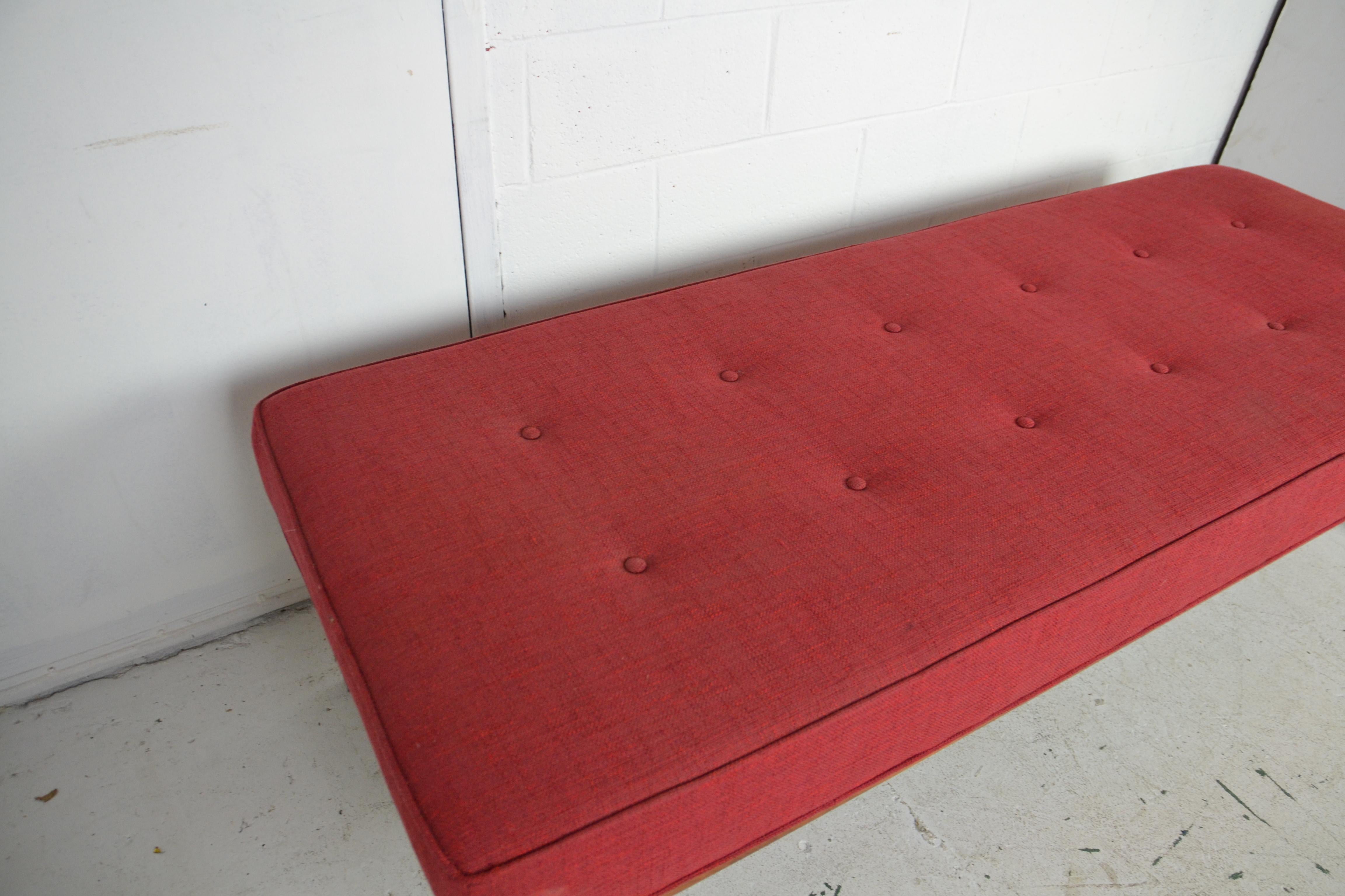 A large mid-century upholstered teak-wood bench.