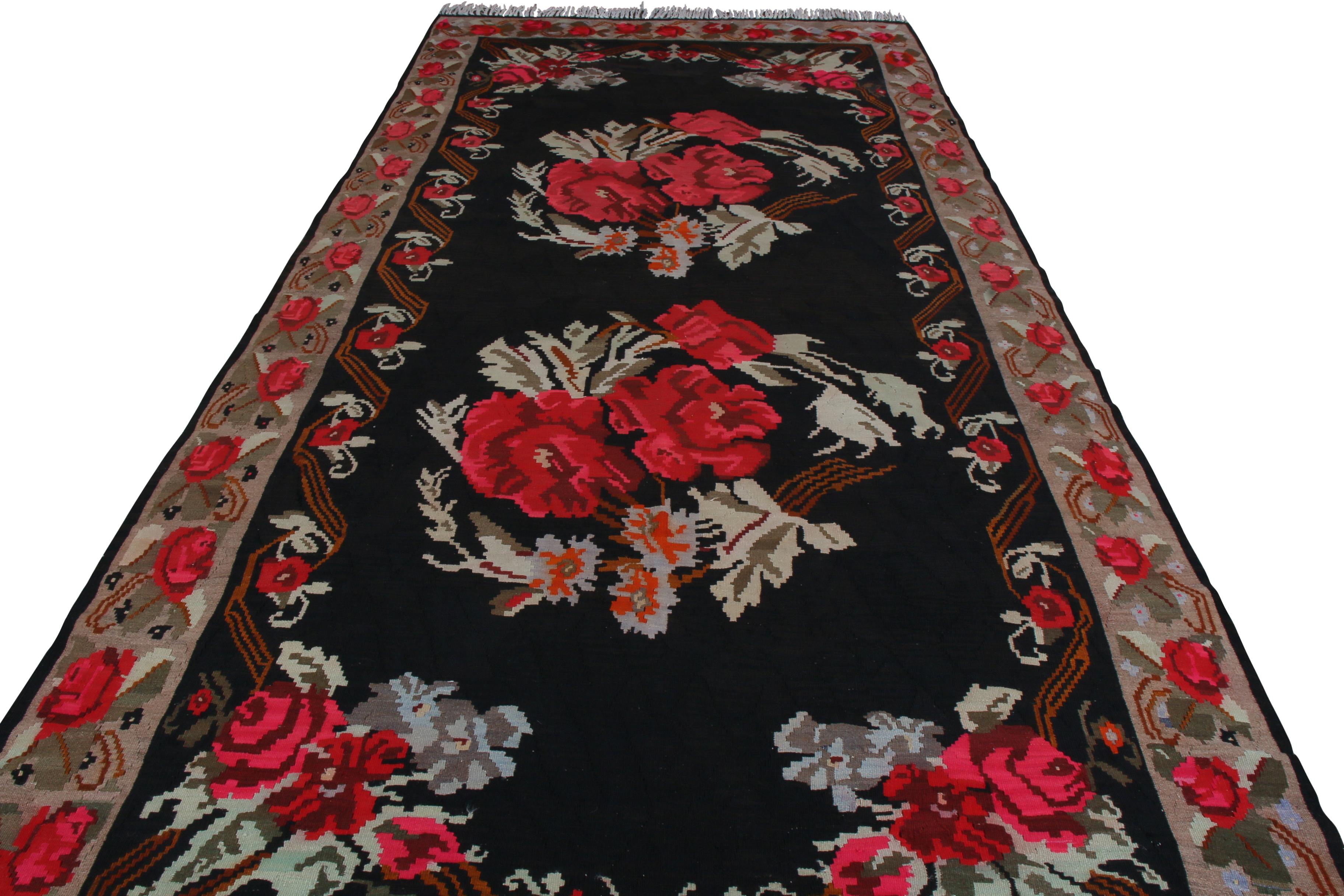 Handwoven in wool originating from Turkey circa 1950-1960, this item is a vintage floral Bessarabian kilim, affording a romantic touch to a room akin to the Romanian kilim style inspired in its design. On a black background, two bouquets of bright