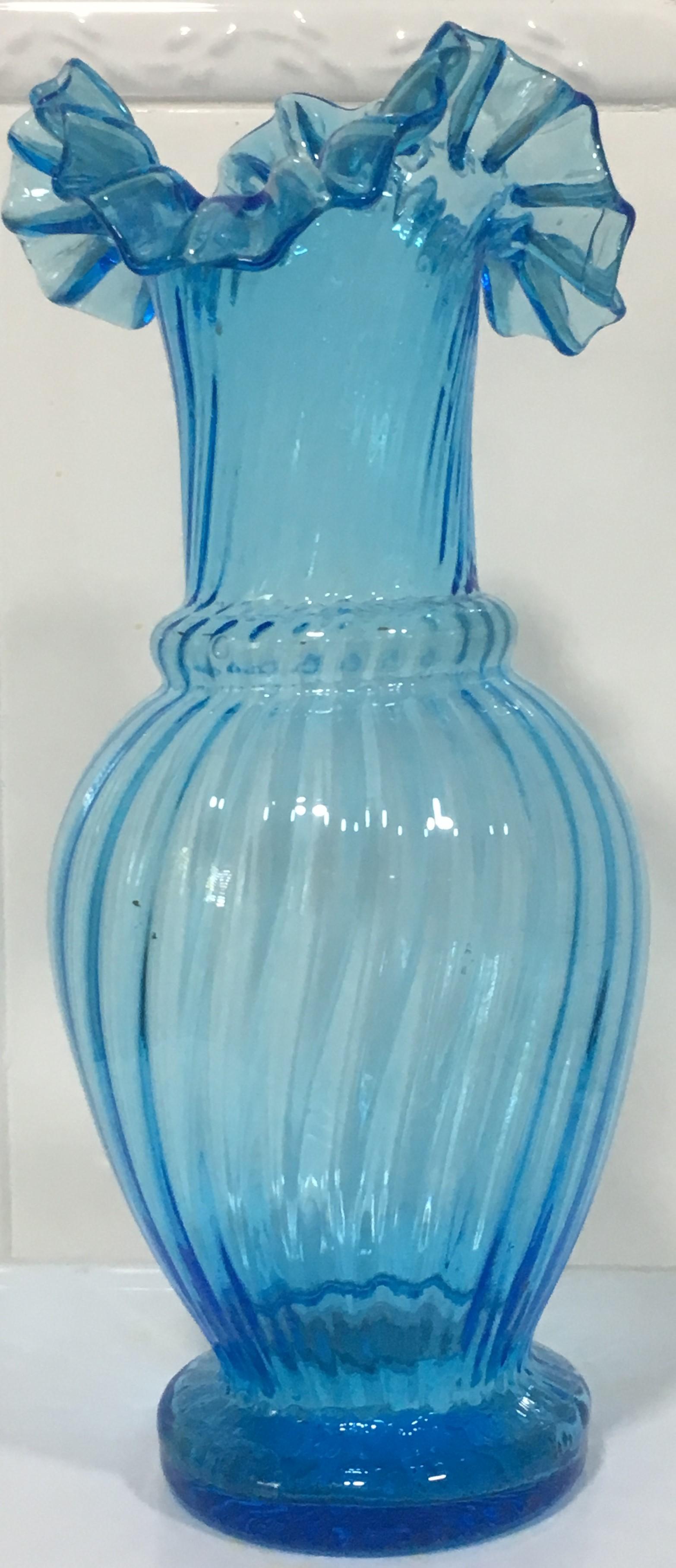 Biedermeier style glass vase light blue.

Mouth-blown vase made of light blue tear-off glass, artfully twisted with ruche-like upper finish.
 