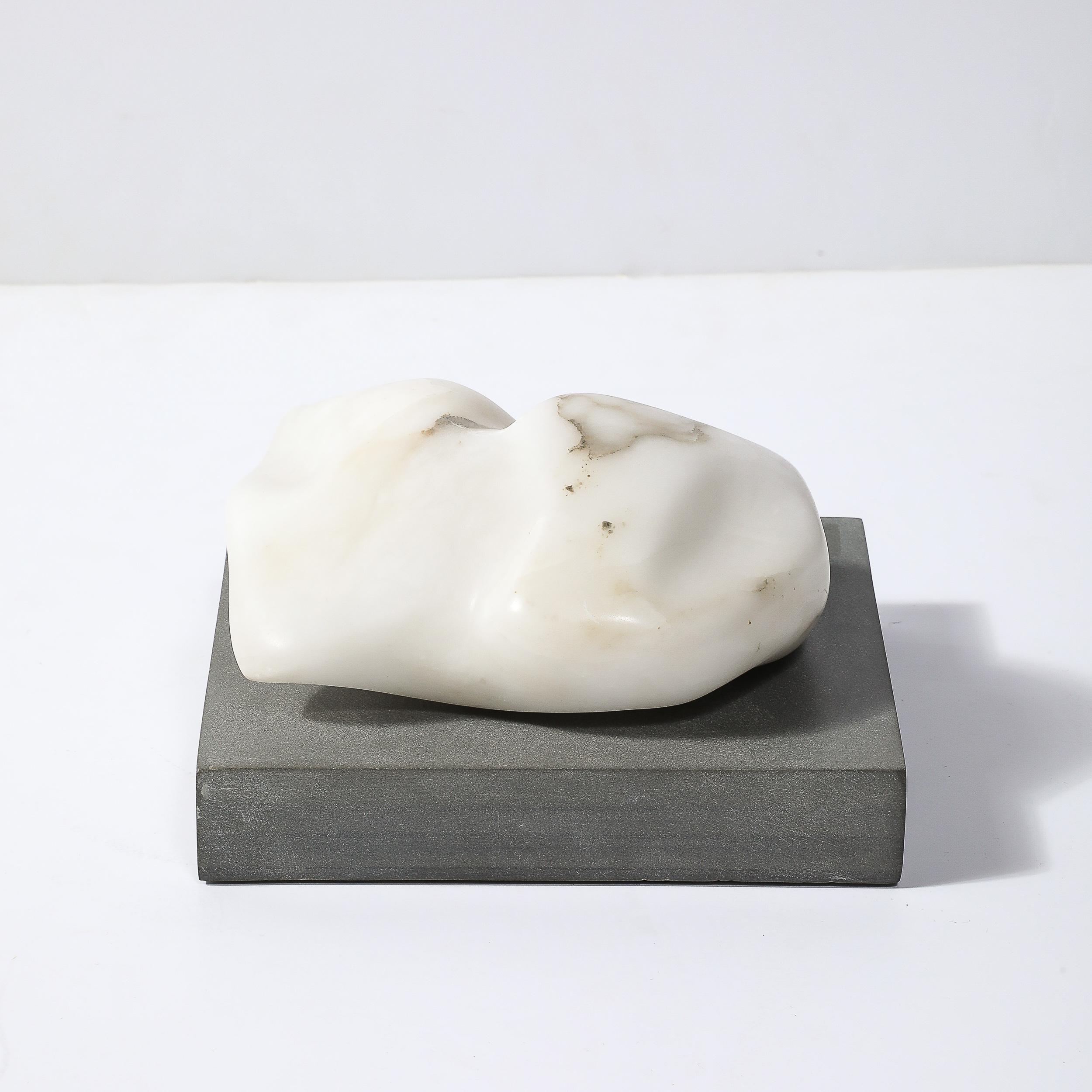 Questa graziosa scultura biomorfa in pietra scolpita del Mid-Century Modernist su una base d'ardesia rettilinea proviene dagli Stati Uniti, circa 1960. Posizionata su una solida base rettilinea in ardesia, la scultura ottiene una base contrastante