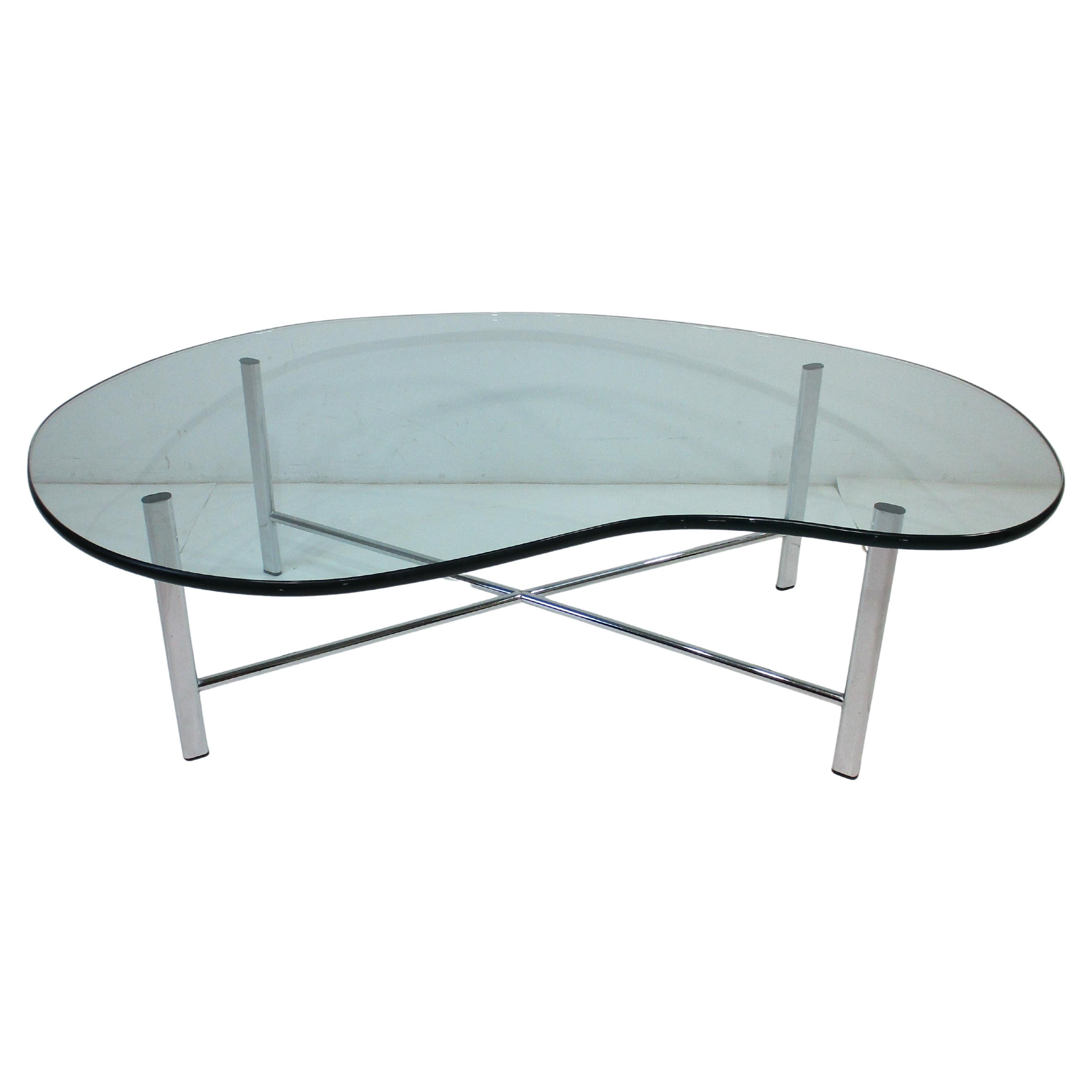 A Mid Century 1970's coffee table with sculptural biomorphic plate glass top and chromed X based . It's clean lines and interesting form can work with any interior or with many styles like space age , modern or mid century , 
designed in the manner
