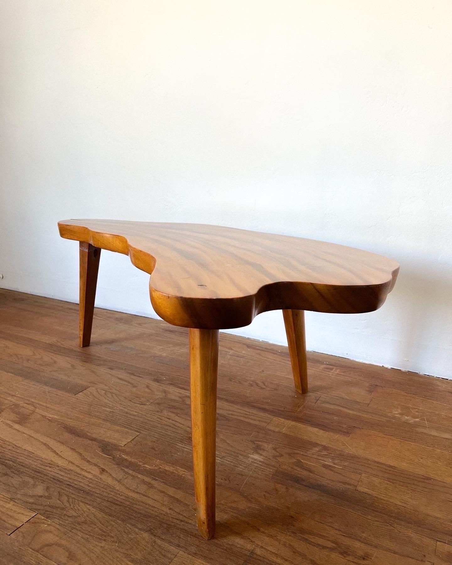 Magnifique table basse à trois pieds en bois massif de Koa épais, de forme libre, plateau massif laqué brillant. Il repose sur trois pieds solides laqués. Beau grain et forme unique, très bel état et propre.