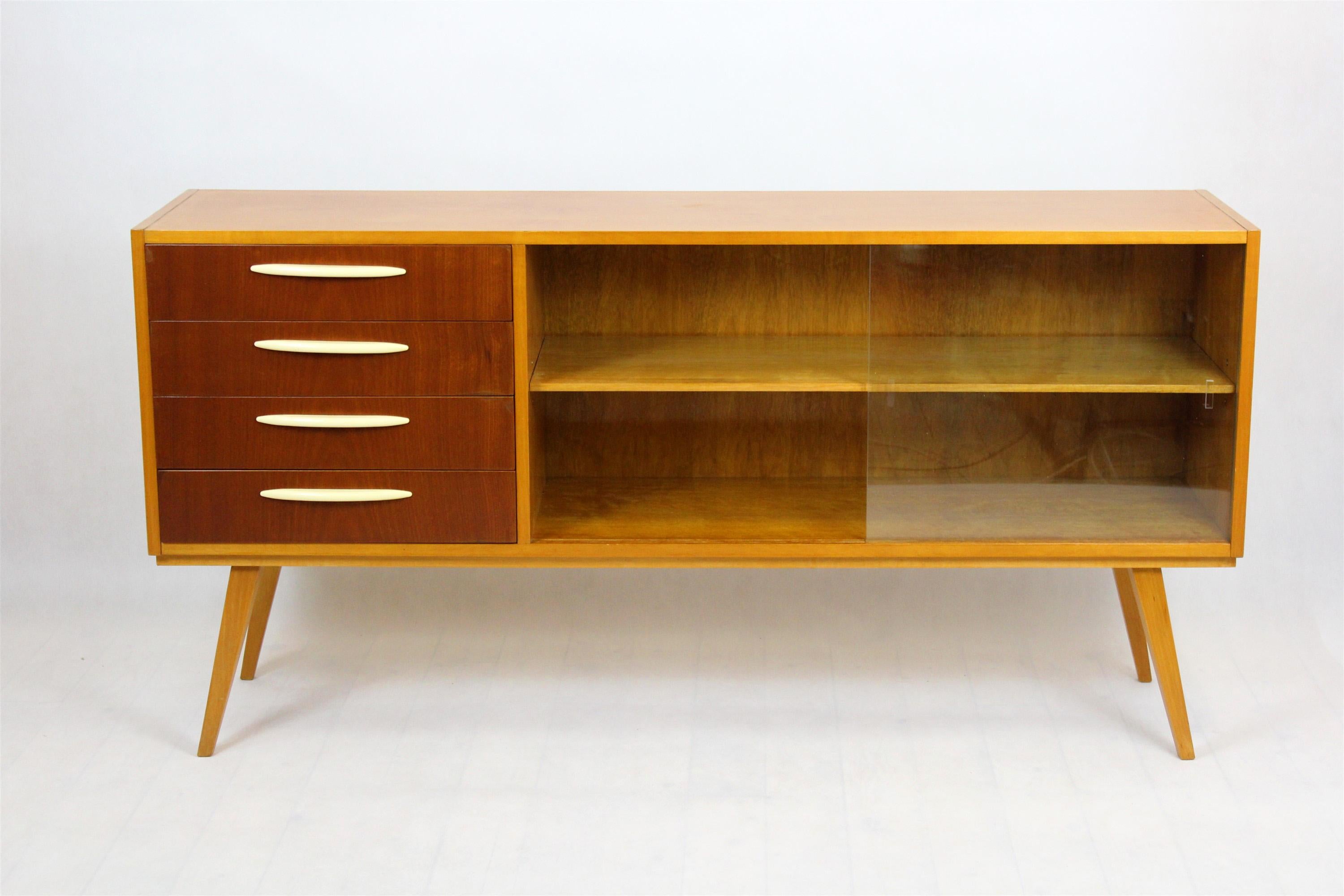 This vintage sideboard was produced in the 1960s in Czechoslovakia. A combination of light and dark elements, thanks to veneering with two types of wood (birch and mahogany). Preserved in good condition, fully functional.
   