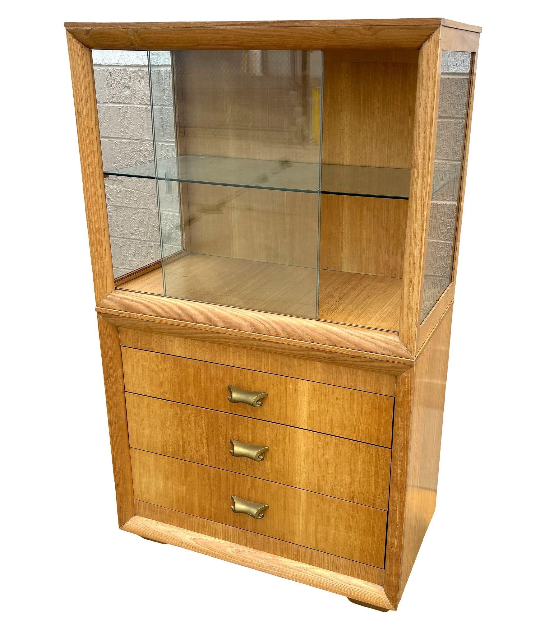 Original Birch curio cabinet and drawers with bronze scrolling drawer pull feature a sleek cubist mid-century design fashion after Edward Wormley's ‘Precedent’ furniture collection. It offers 2 shelf cabinets with glass-fronted doors on top of 3