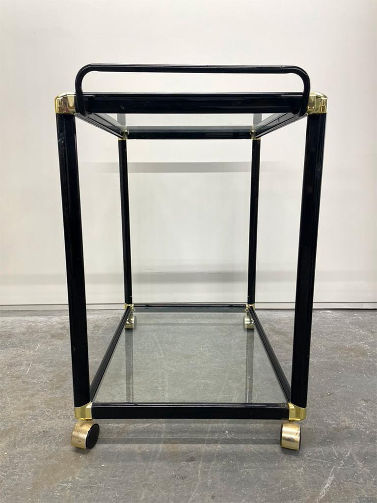 Vintage Mid-Century Modern black metal bar cart with brass accents and removable glass shelves. The wheels are original to the cart. This piece would make a great addition to anyones living room as a side table or a dry bar.