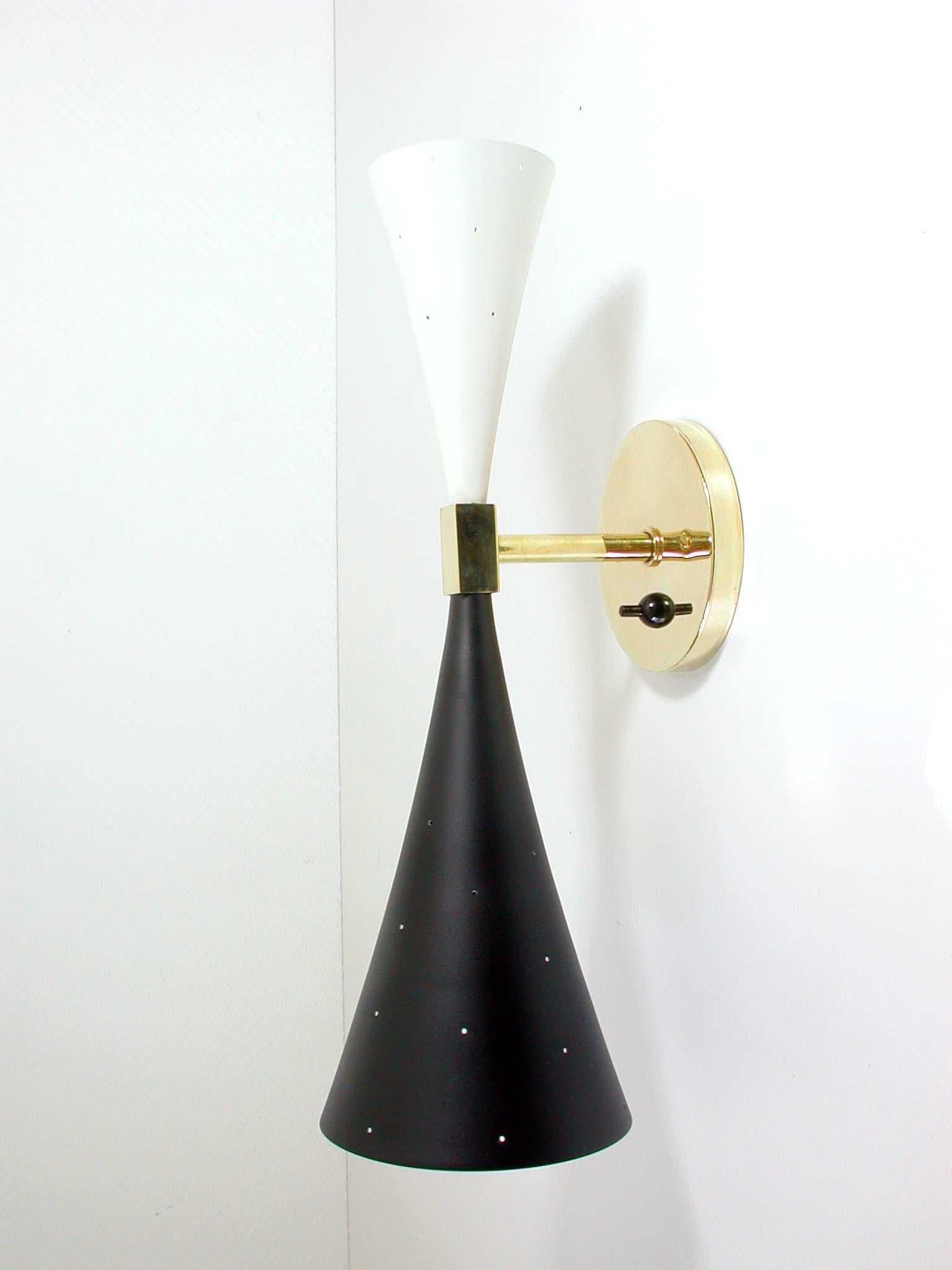 This large Modernist 1950s double cone wall light was designed and manufactured in the United States.

The wall light has got a black and a white diabolo-shaped perforated lampshade with brass lamp rod and brass backplate (diameter 4.5 inches /