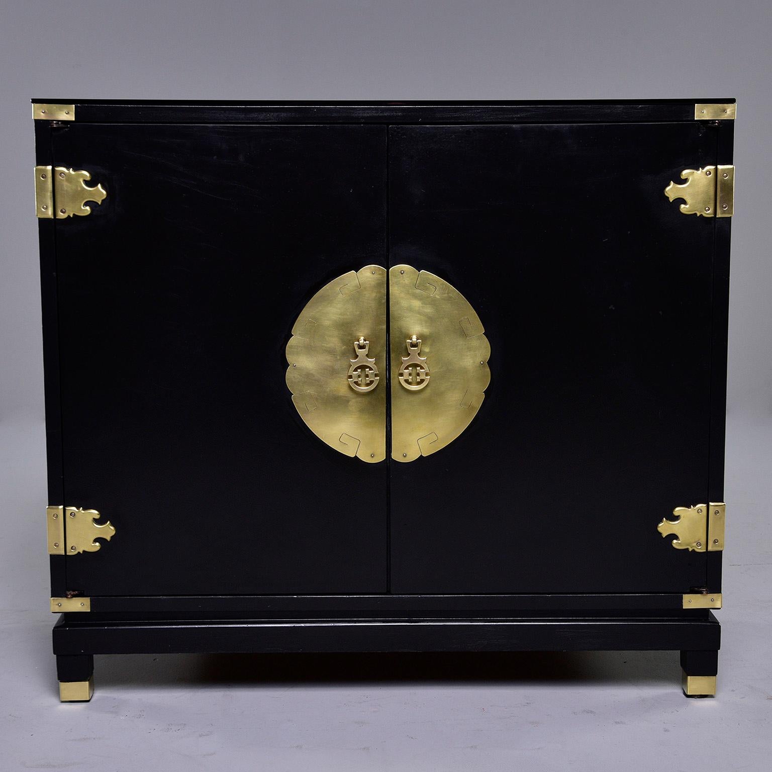 Asian-style cabinet by Permacraft of Sanford, NC, circa 1960s. Smaller, cabinet has single internal shelf and drawer, brass capped feet and all original brass hardware. New custom cut black glass top and professional paint job. Versatile size - can