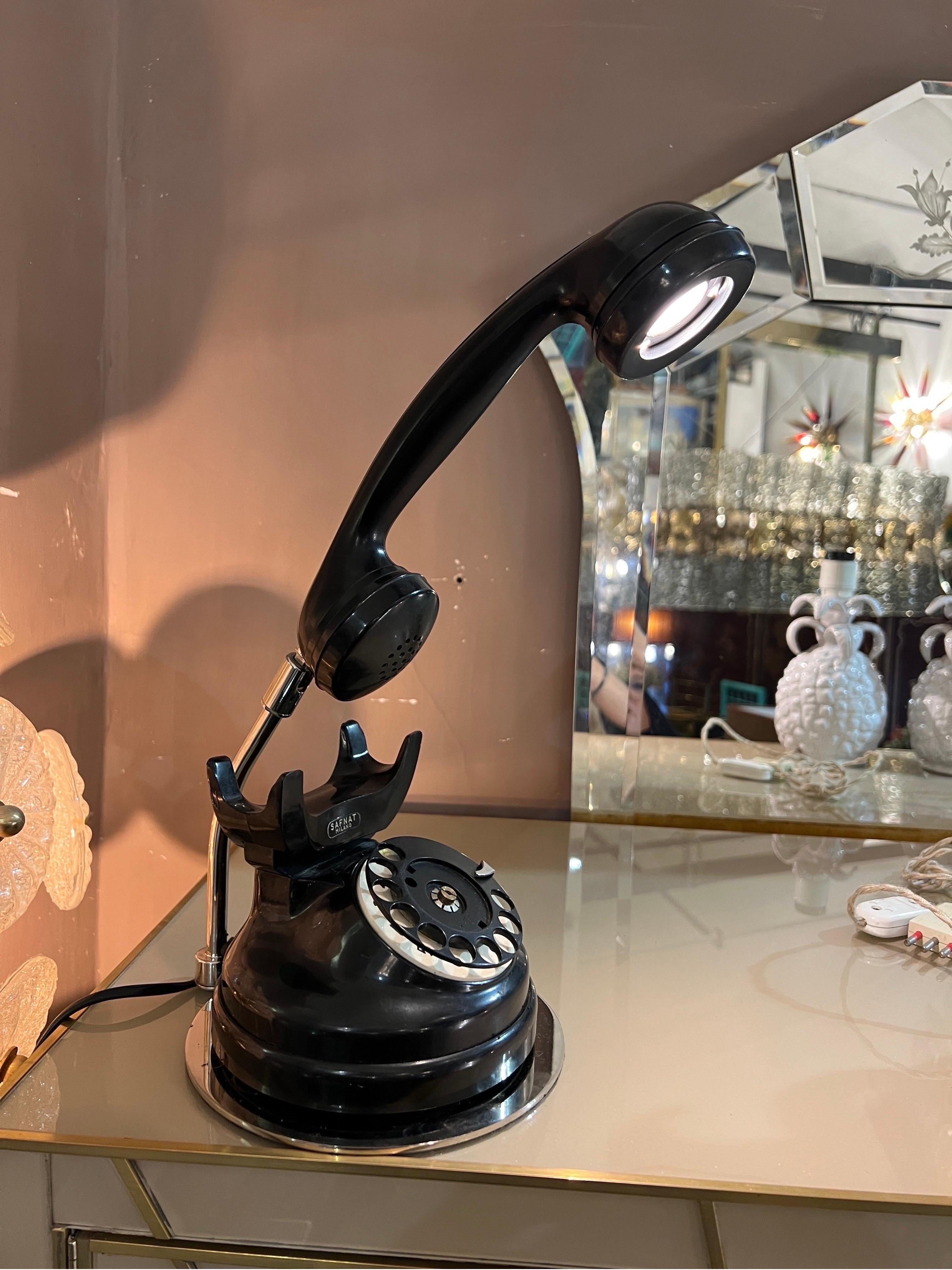 Lampe de table téléphonique en bakélite noire du milieu du siècle dernier, signée Safnat Milano.
Le téléphone est doté de raccords chromés.
Un voyant lumineux dans le combiné du téléphone.
Il a été recâblé avec une lumière LED mais le bouton